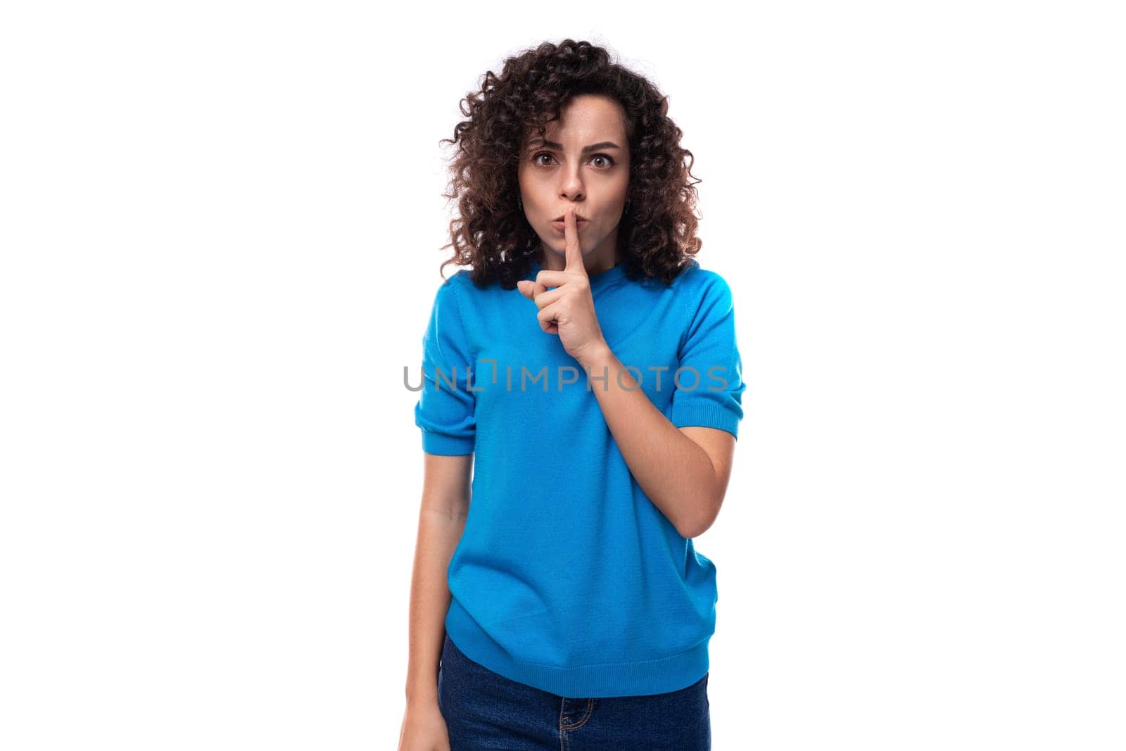 young brunette lady with curly hair dressed in a blue blouse keeps a secret.