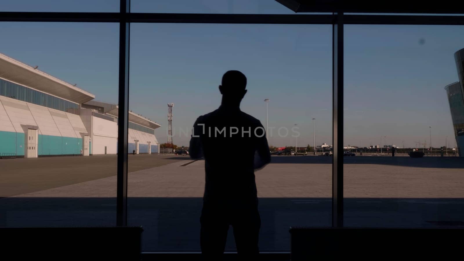 Rear view of a man silhouette at the shopping center going to the panoramic window. Hdr. Unrecognizable man at the window