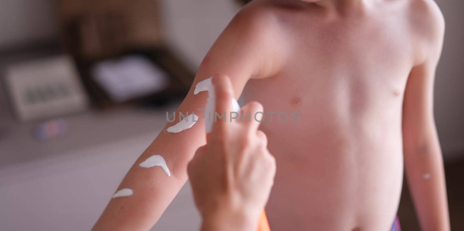 Mother applying sunscreen to baby skin closeup. Sun protection for baby skin concept