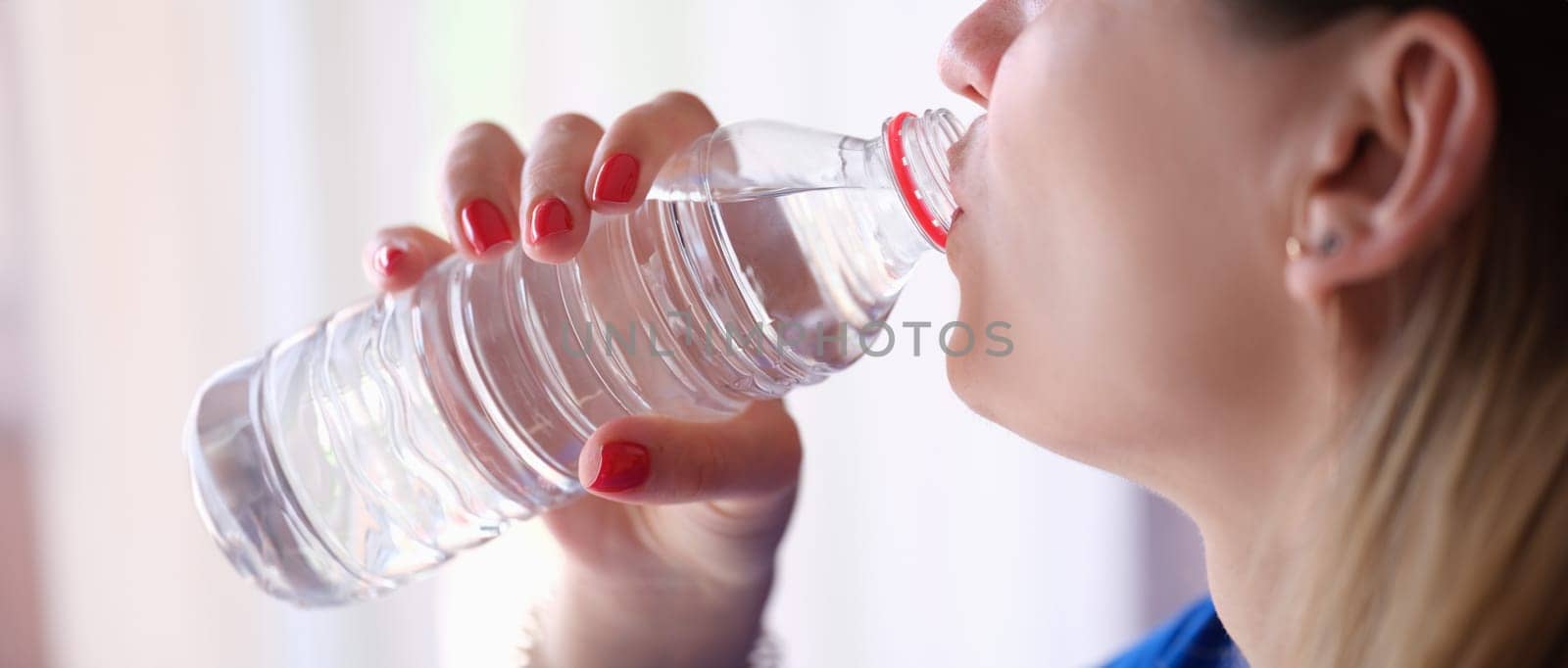 Woman drinking water from plastic bottle closeup by kuprevich