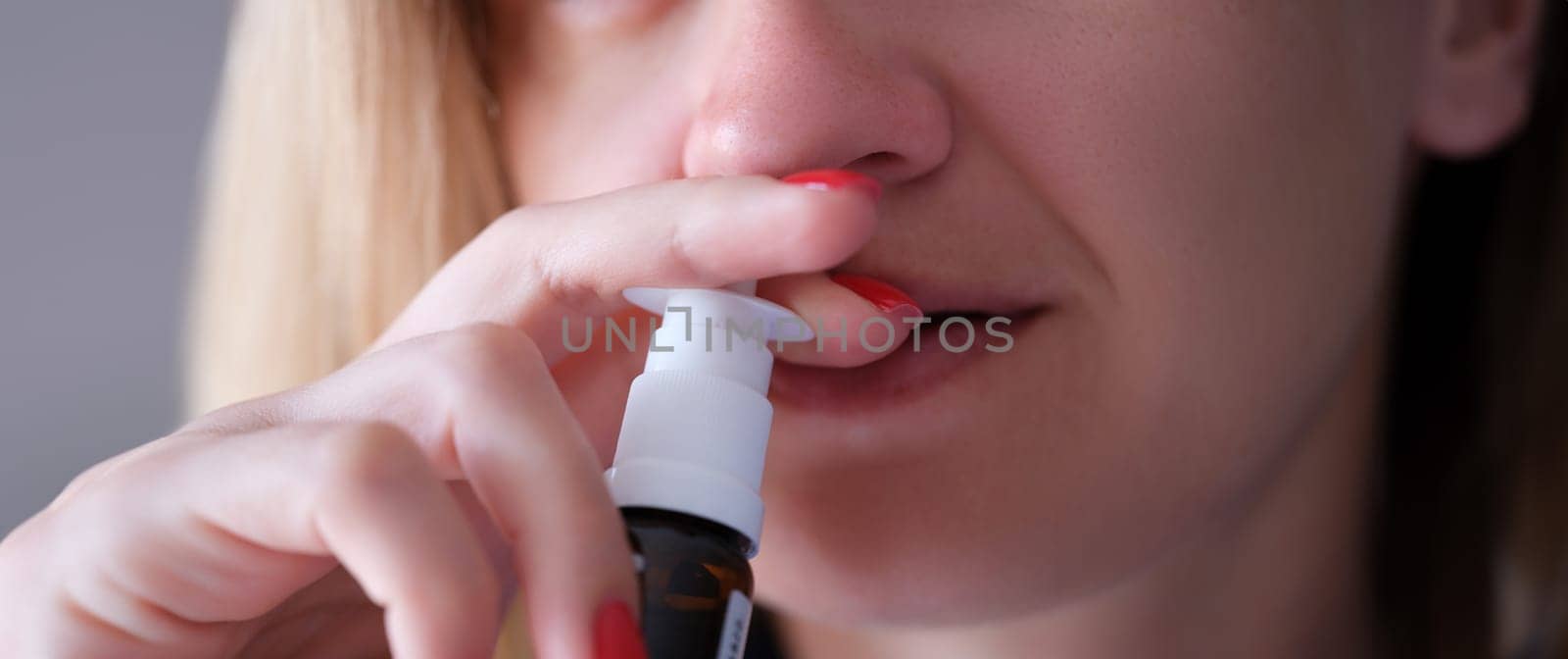 Woman instilling her nose with vasoconstrictor drops closeup. Acute sinusitis treatment concept