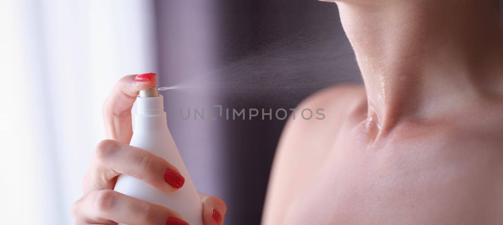 Woman with red manicure applying perfume on her neck closeup. Selection of women toilet water concept