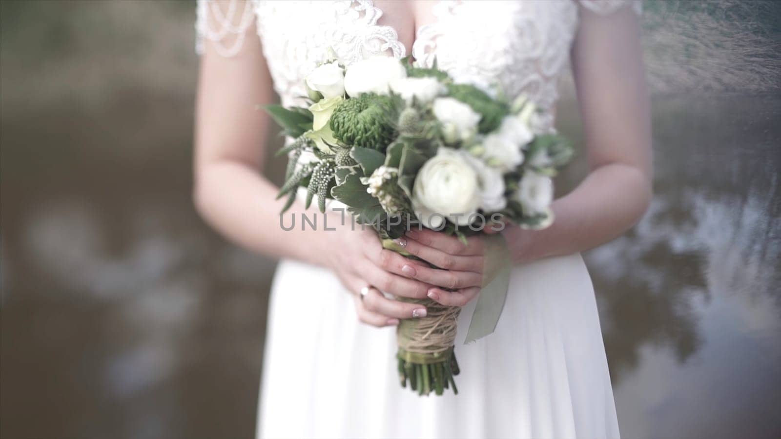 Beautiful bouquet of different colors in the hands of the bride in a white dress. Bride in white dress with bouquet. Woman holds wedding bouquet. Wedding HD