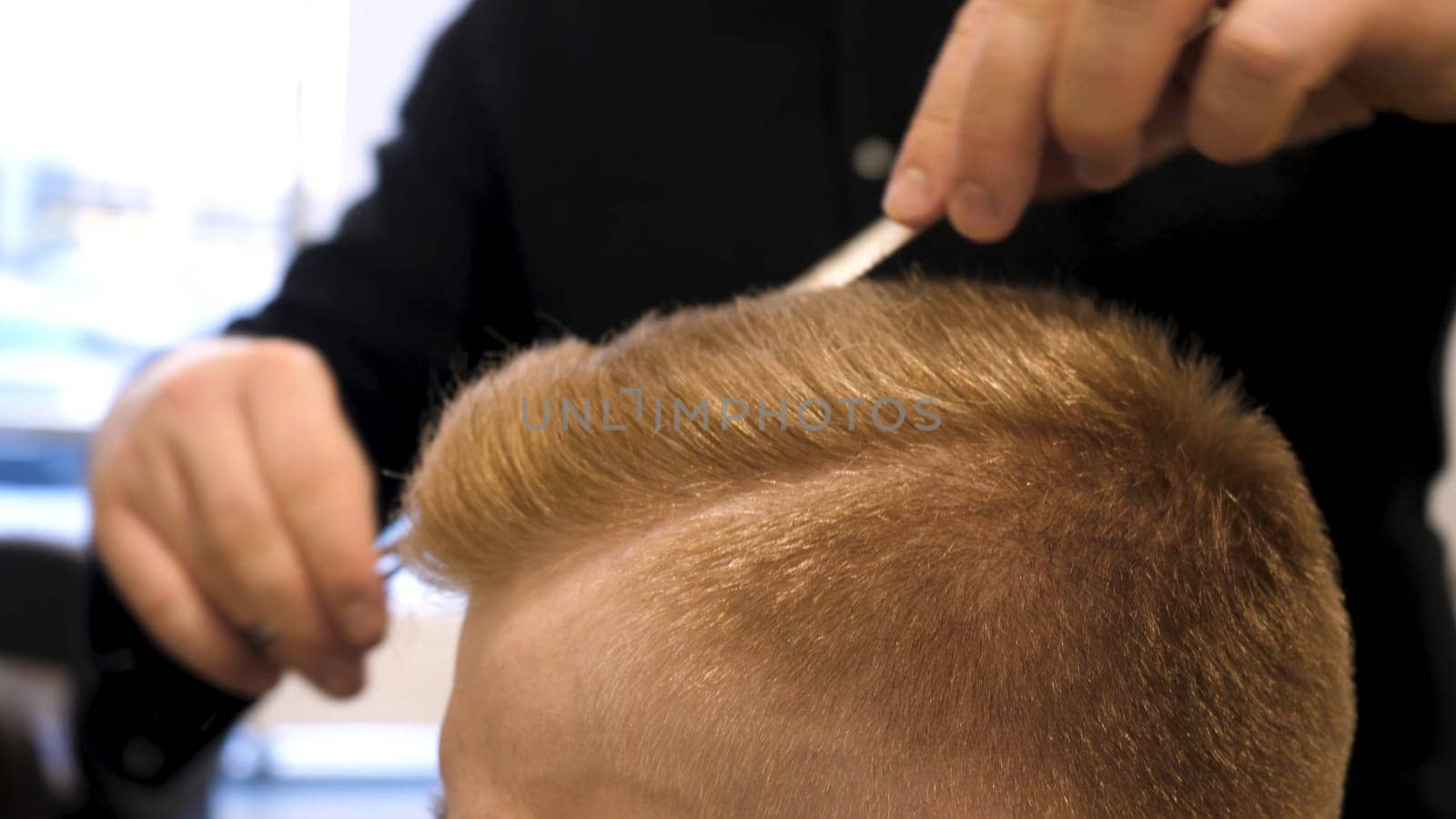 Close up of men's hair cutting scissors in a beauty salon. Master cuts hair and beard of men in the barbershop, hairdresser makes hairstyle for a young man. Close up of Man at the Hair salon.