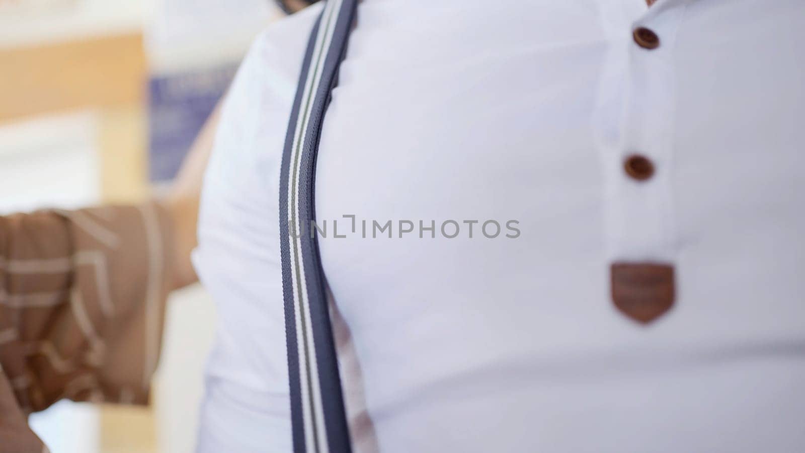 Close up of a man chest in white shirt and blue suspenders. Action. Stylist woman preparing male model before the photo session