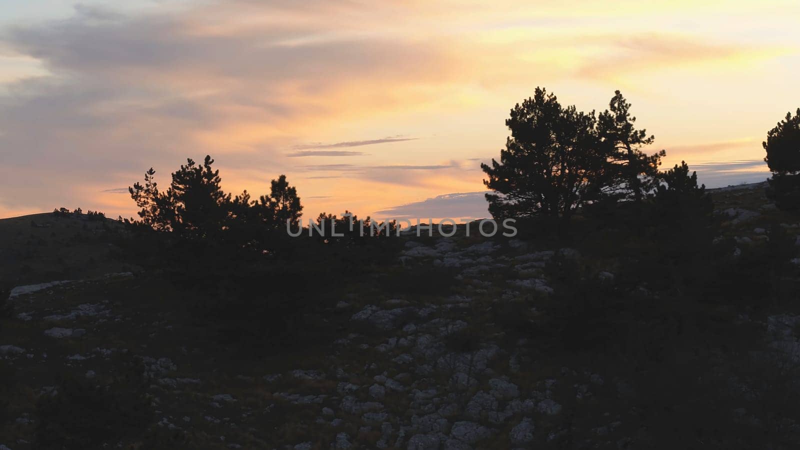 Top view of rocky top on background of sunset colors with clouds. Shot. Colorful picturesque landscape of sunset sky with clouds.