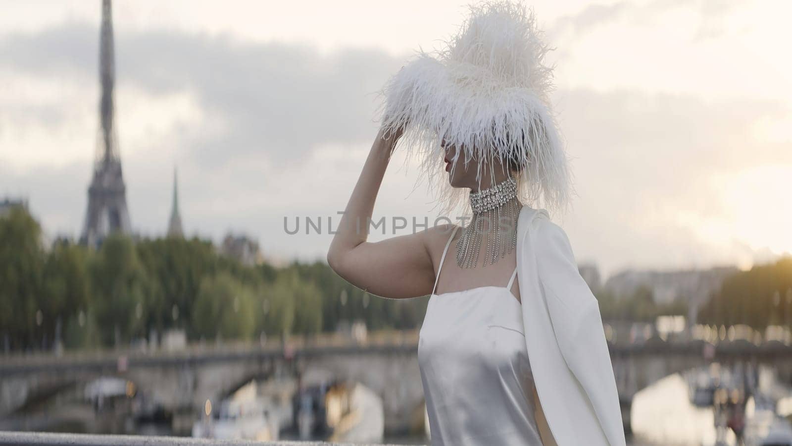 An elegant woman with a feather hat. Action. A cute model with makeup and bright red lips who poses with accessories in clothes. High quality 4k footage