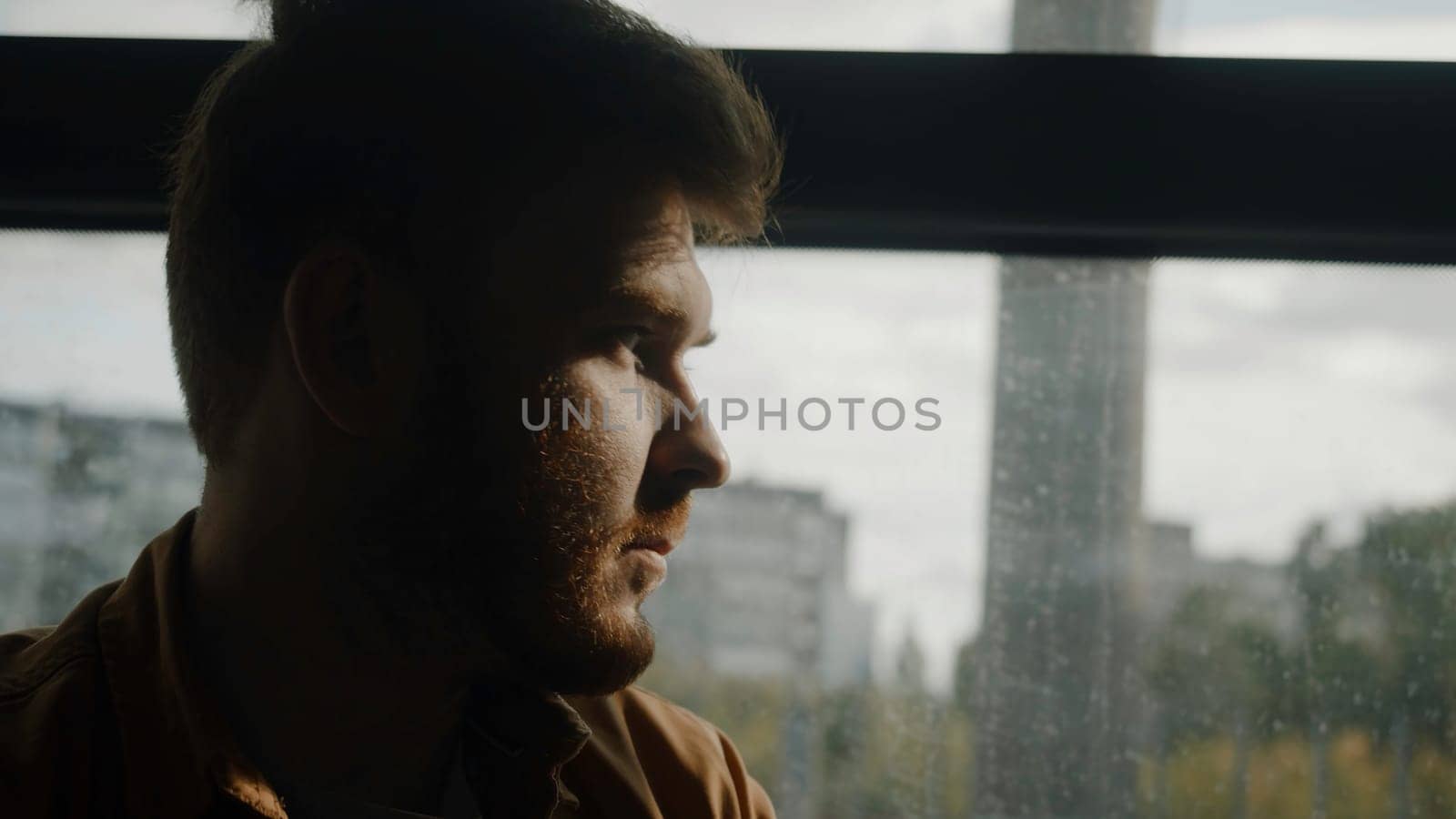 A beautiful portrait of a man. Stock footage. A man on a bus looks at the rays of the sun near the park. High quality 4k footage