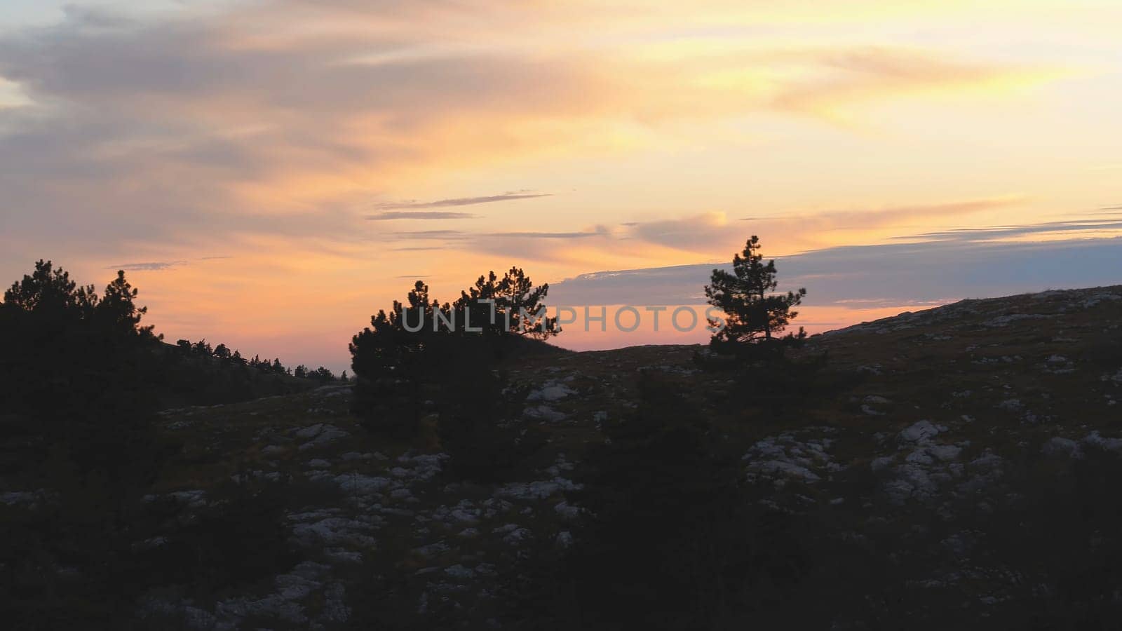 Top view of rocky top on background of sunset colors with clouds. Shot. Colorful picturesque landscape of sunset sky with clouds.