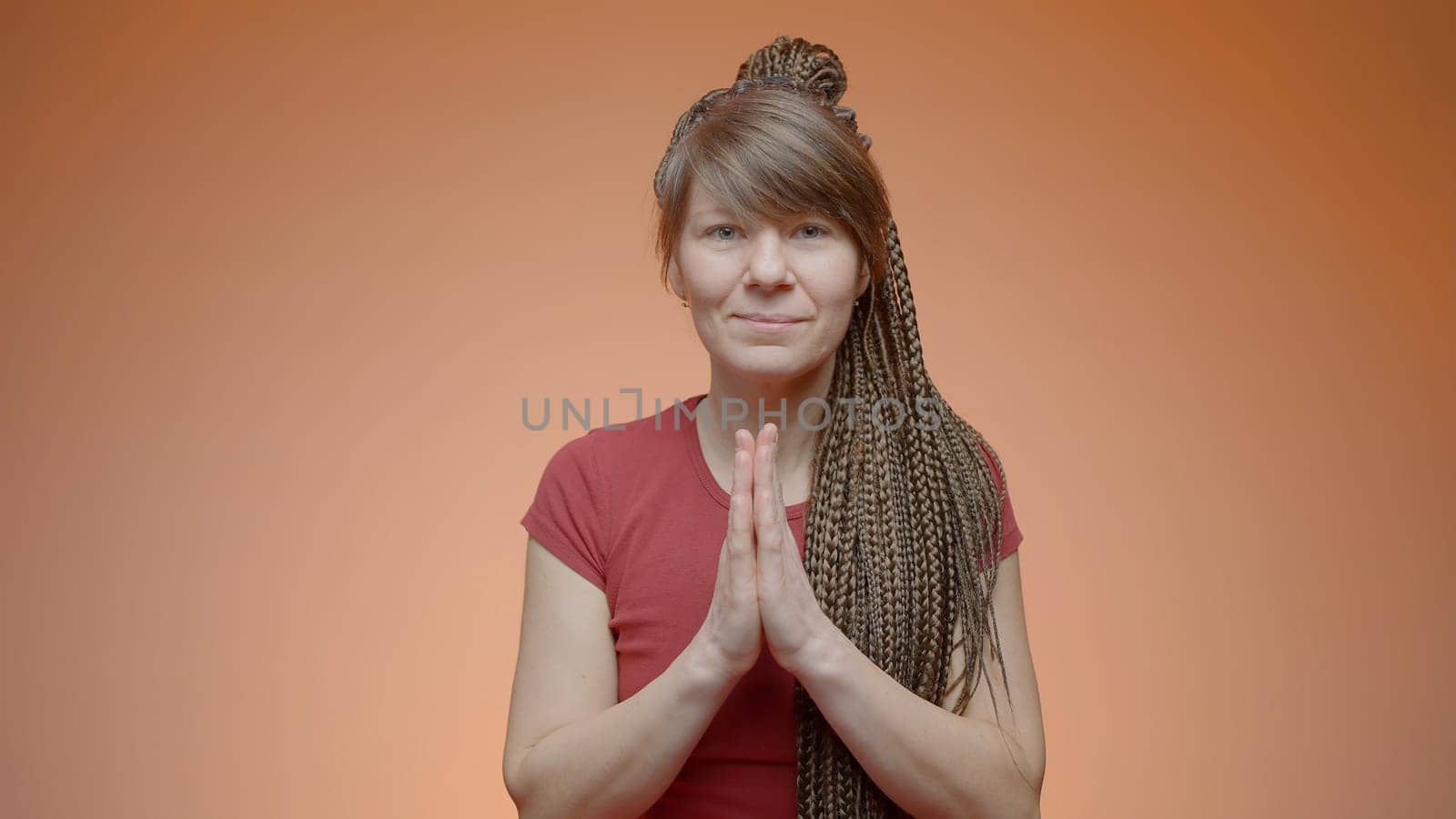 Woman greets with folded hands. Action. Yoga greeting with gratitude. Woman greets in Buddhist way on isolated background.