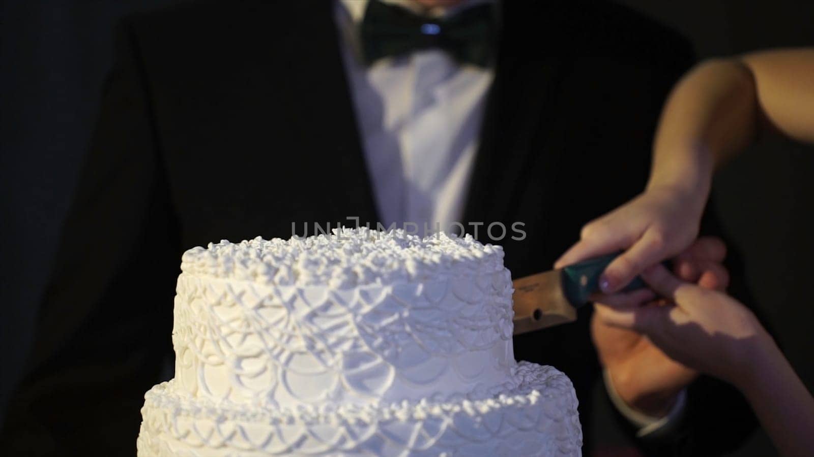 hands of bride and groom cut of a slice of a wedding cake. Bride and Groom at Wedding Reception Cutting the Wedding Cake. The bride and groom cut the wedding cake HD