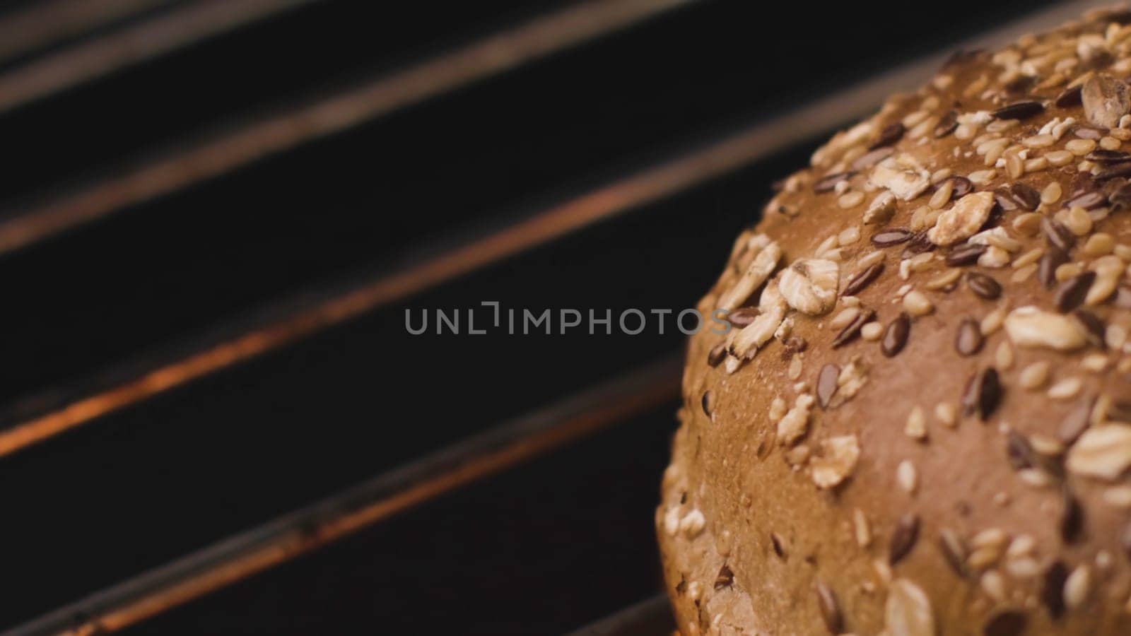 Close-up of hot Burger bun on grill. Stock footage. Delicious grain bread is grilled. Bun on grill for tasty Burger. Round loaf of bread to roast on fire.