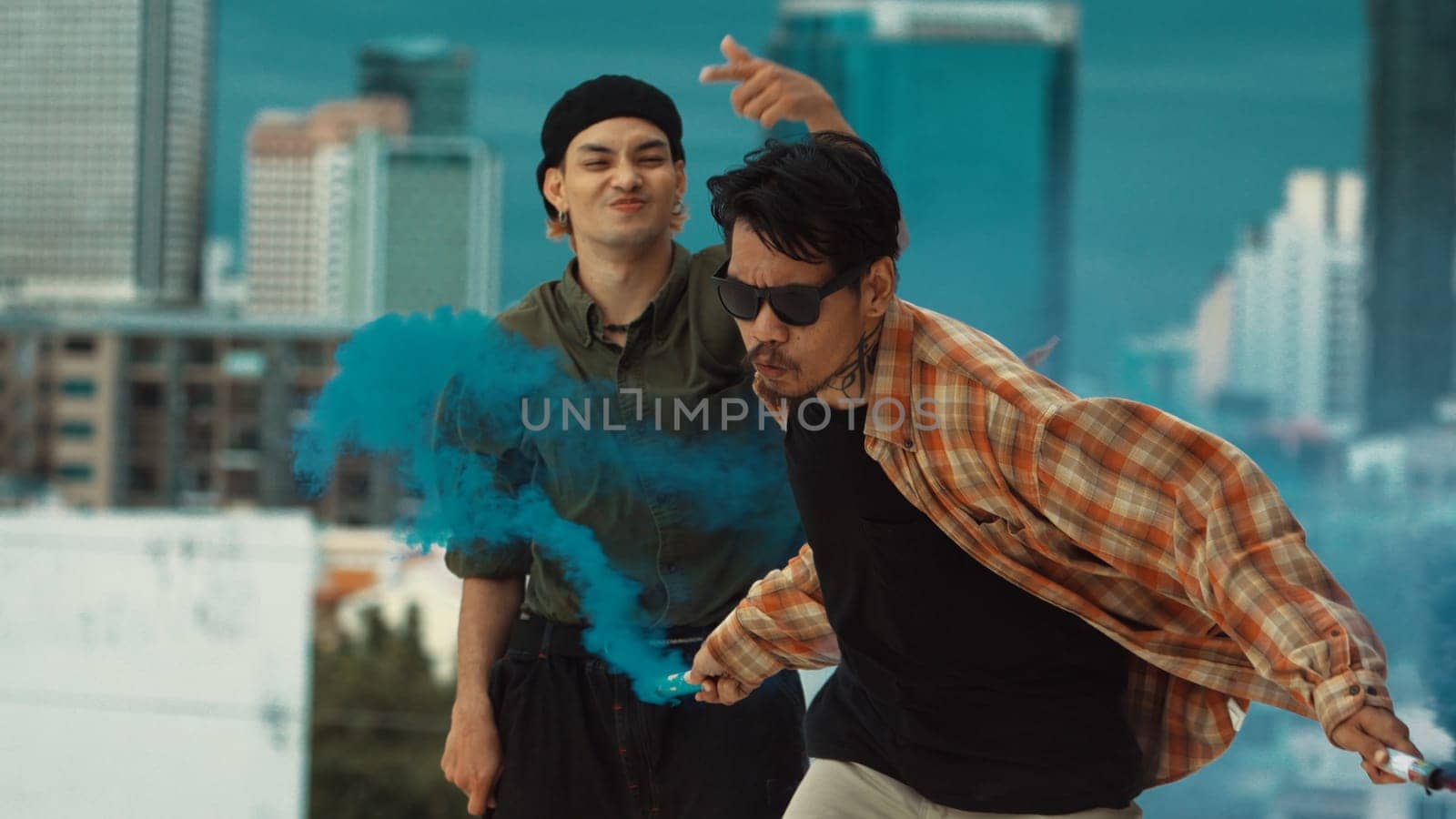 Group of multicultural hipster playing color flare at rooftop. Attractive street dancer holding colored smoke and perform break dance move to hip-hop music. Outdoor sport 2024. Endeavor.