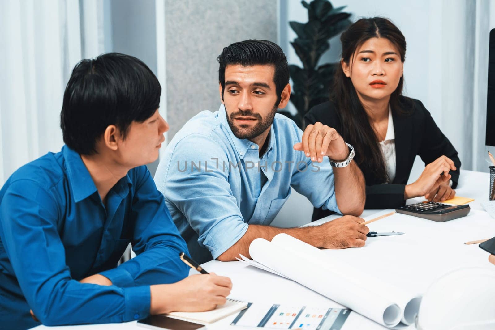 Diverse group of civil engineer and client working together on architectural project, reviewing construction plan and building blueprint at meeting table. Prudent