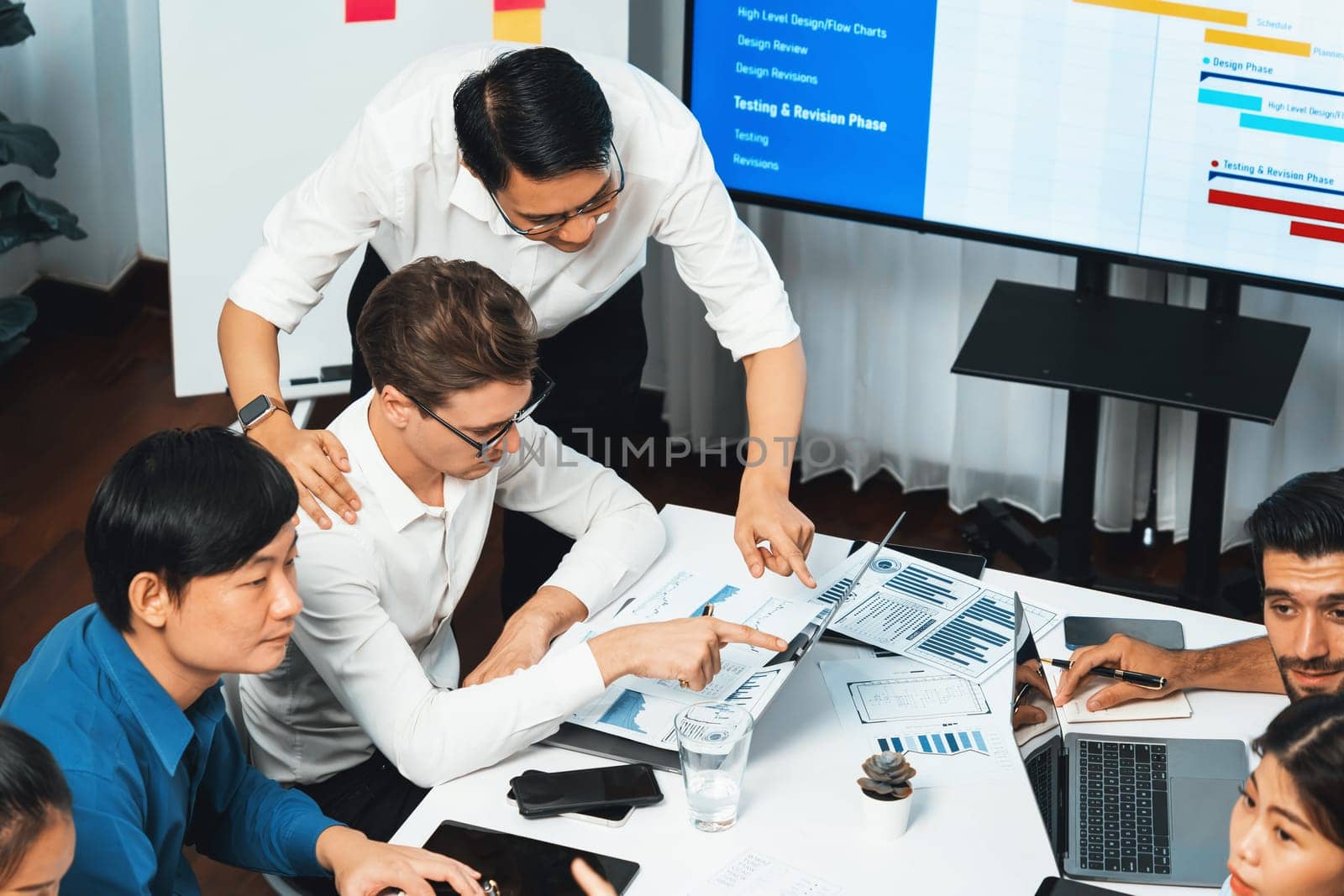 Analyst team utilizing BI Fintech to analyze financial data at table in meeting room. Businesspeople analyzing BI dashboard power on paper for business insight and strategic marketing planning.Prudent