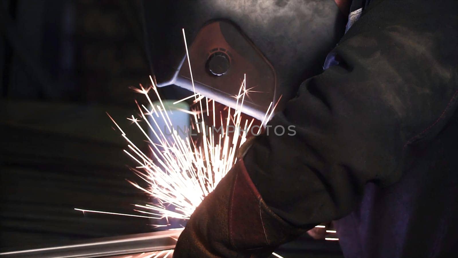 A man works with a welding machine. Clip. Welding steel structures in the factory. Beautiful sparks fly out.
