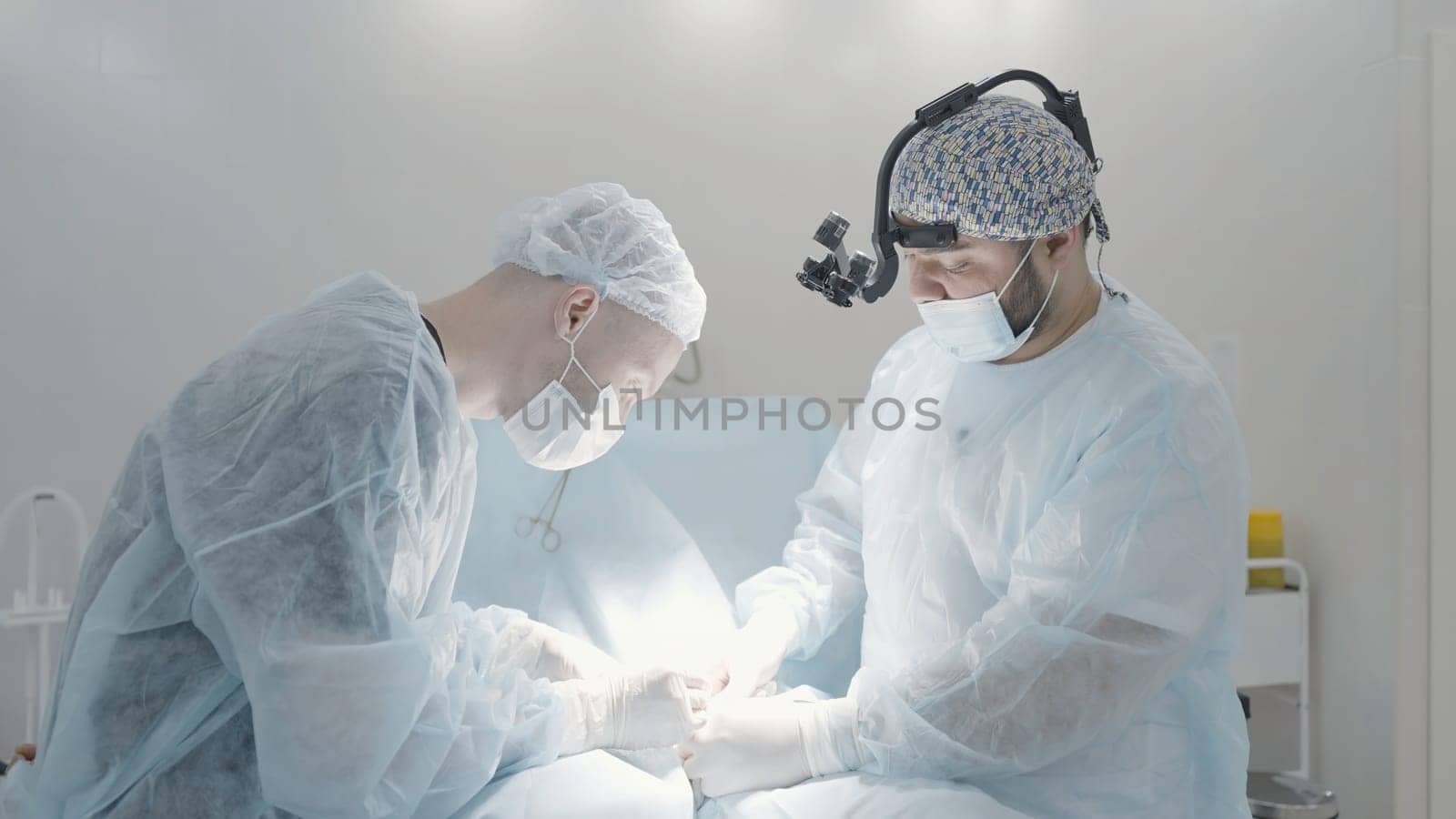 Surgery. Action. Two doctors with special equipment who perform surgical care in a ward illuminated by light. High quality 4k footage