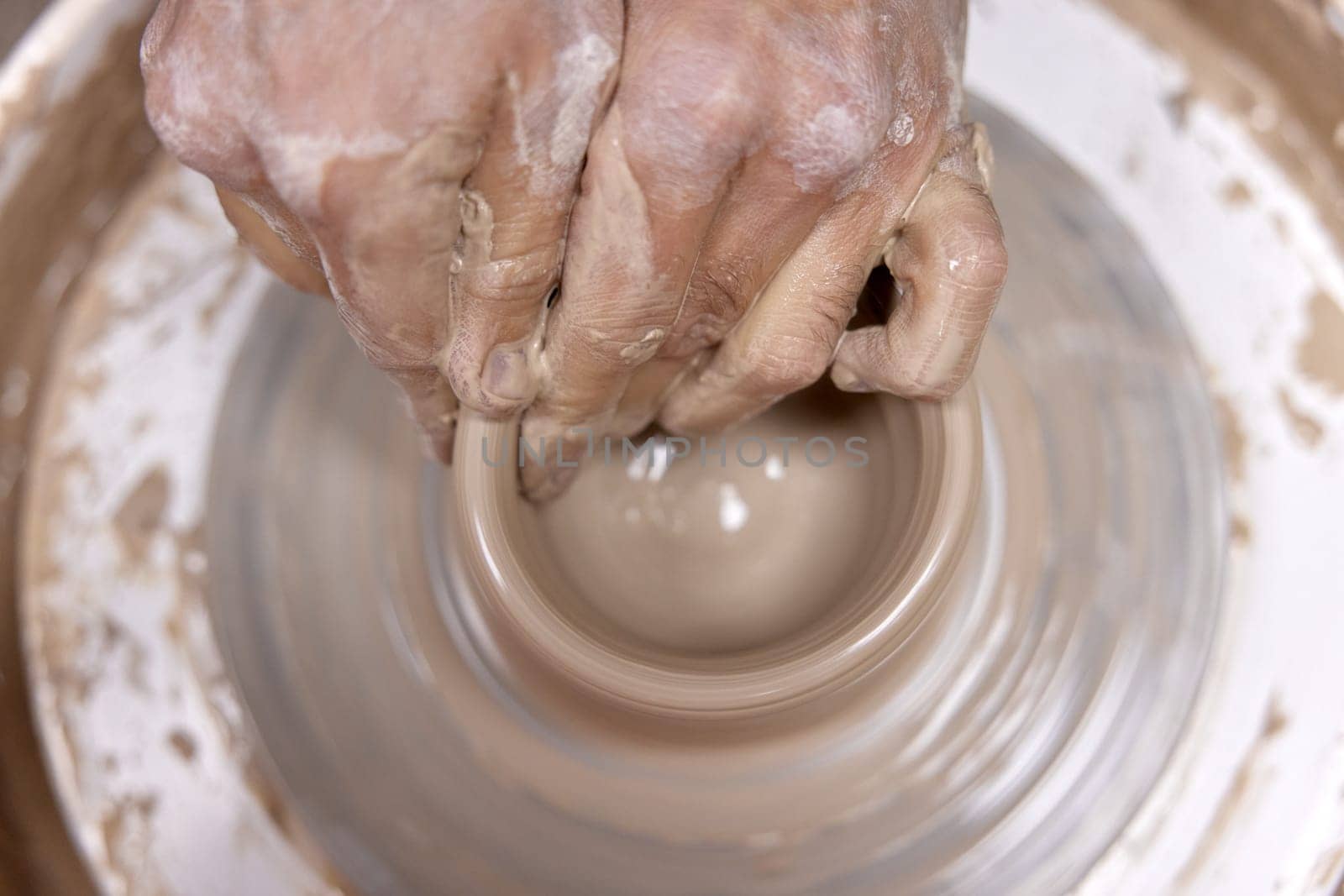 male hands making ceramic cup on pottery wheel, Close-up, top view