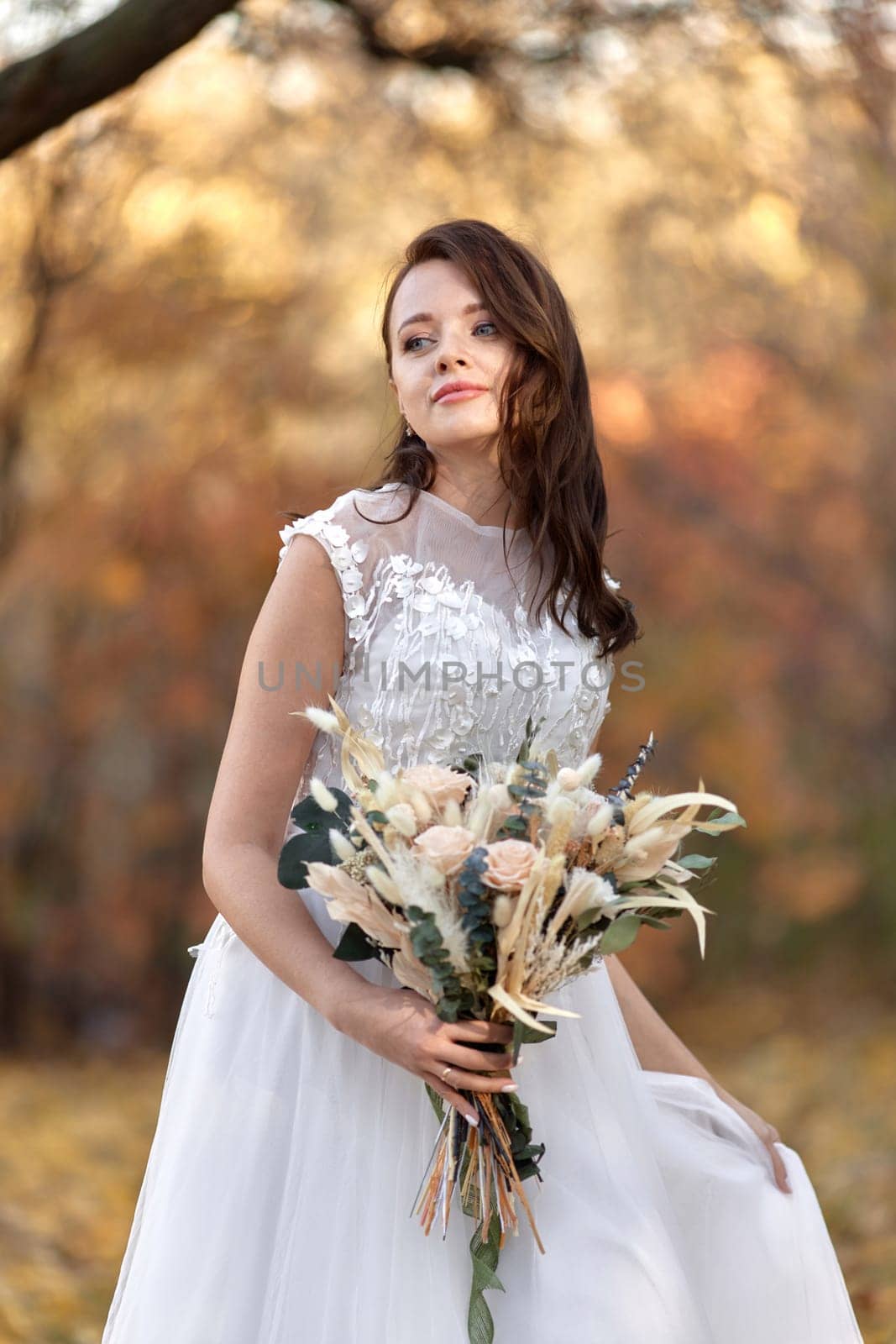 beautiful happy bride holding wedding autumn bouquet in nature