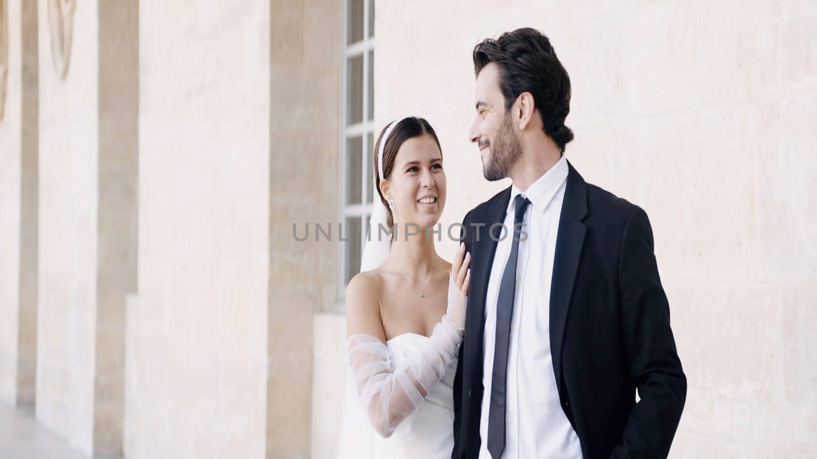 Newlyweds, caucasian bride and groom posing by the building outdoors. Action. Woman in white dress with a man in suit