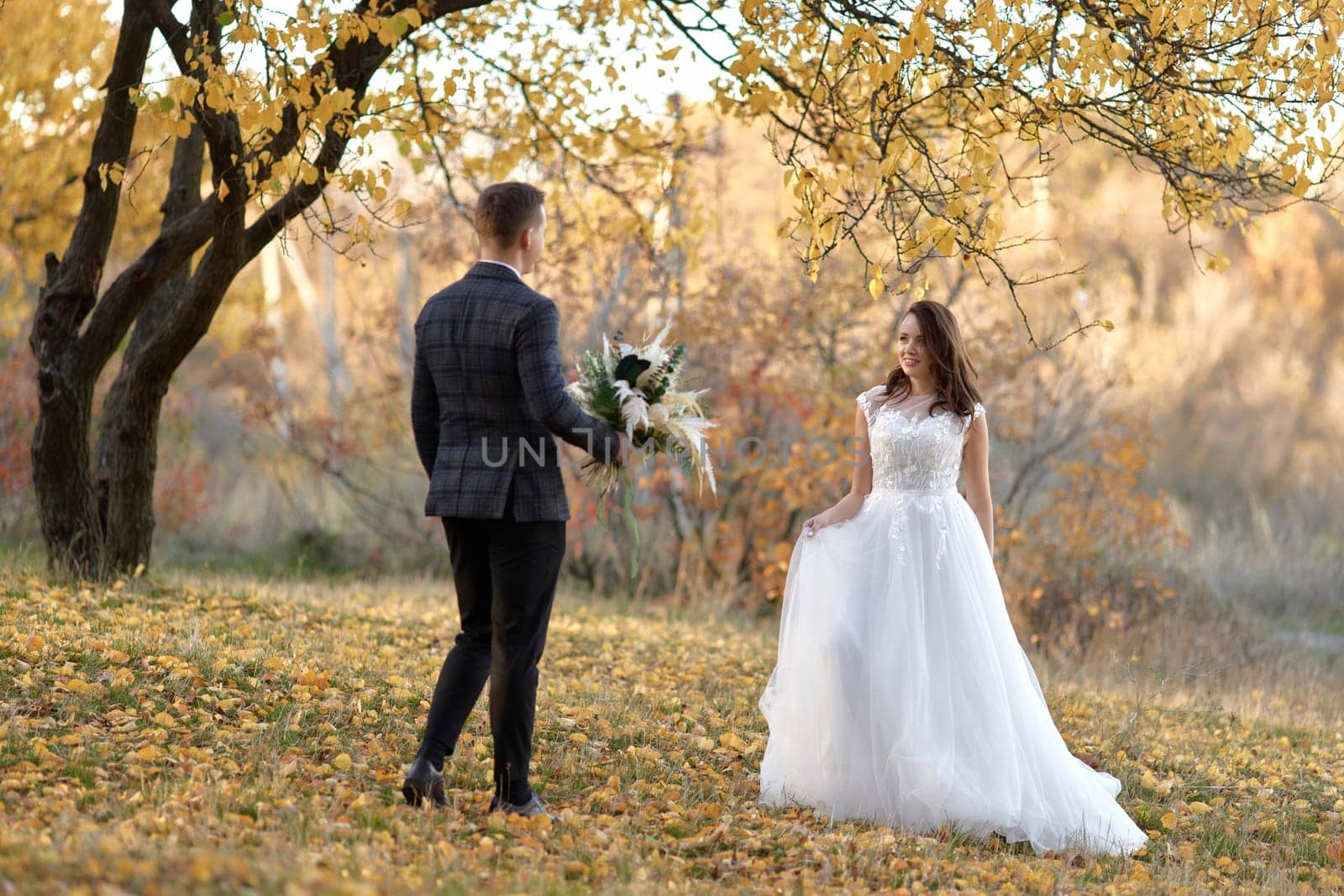 beautiful sensual bride in white wedding dress and groom standing outdoor on natural background