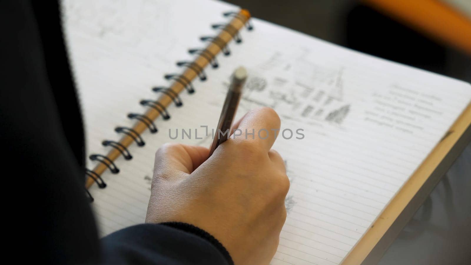 Hands holding pencil to write or to draw in a notebook. Adult colouring with soft tip pencils. Female hand drawing pencil in the notebook close-up p