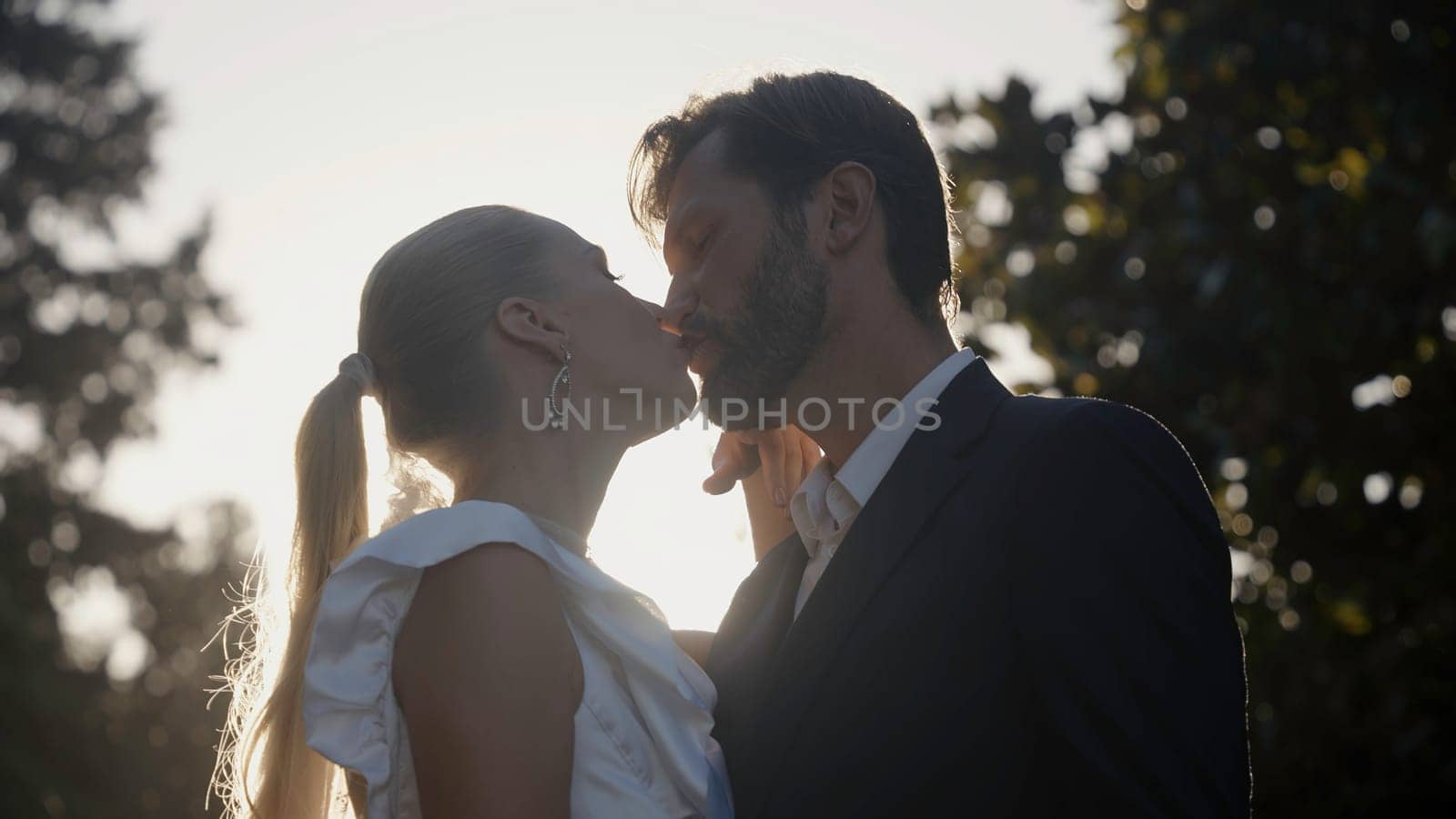 Portrait of charming man and woman newlyweds outdoors. Action. Happy wedding couple in summer garden. Cute bride and groom having fun on wedding ceremony