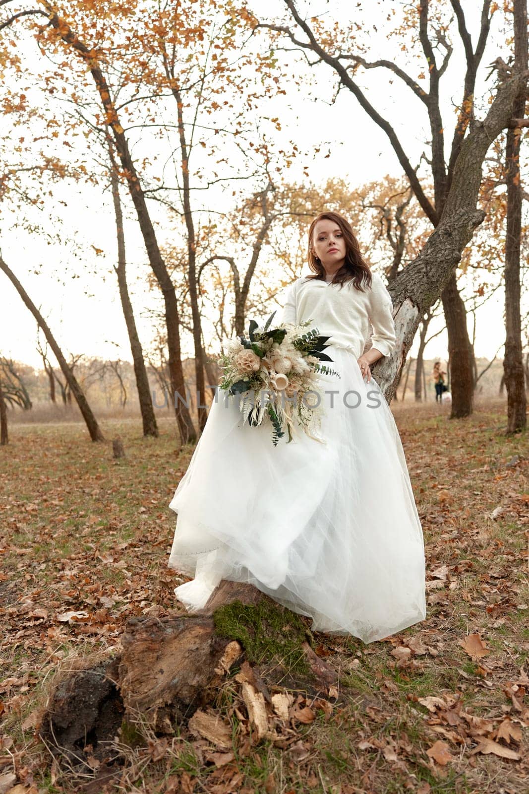 beautiful happy bride holding wedding autumn bouquet in nature