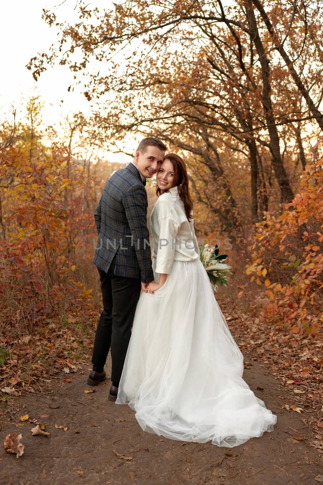 beautiful sensual bride in white wedding dress and groom standing outdoor on natural background