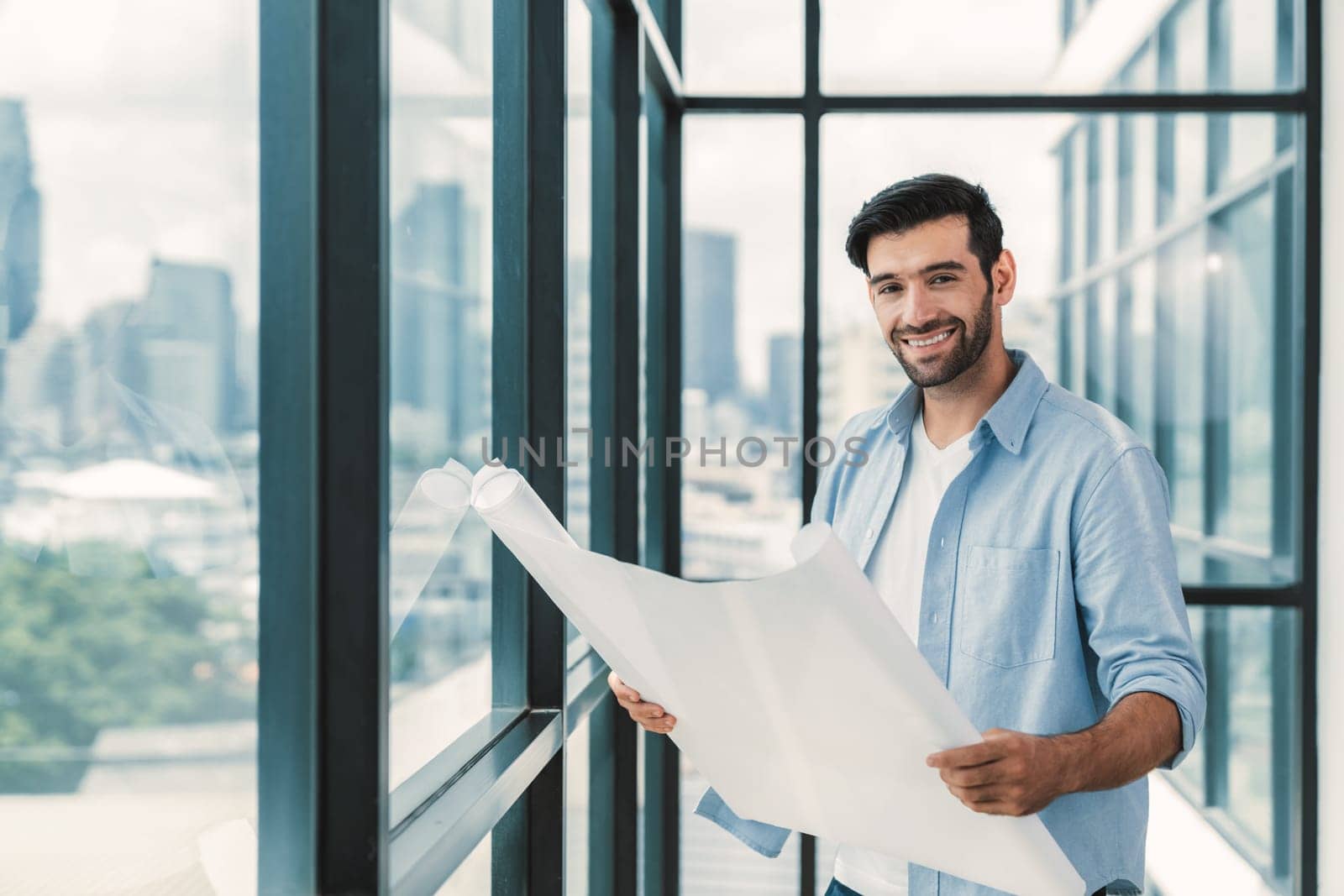 Professional architect engineer or male worker in casual outfit looking at skyscraper and city view while holding project plan. Creative design, civil engineering, building construction. Tracery.