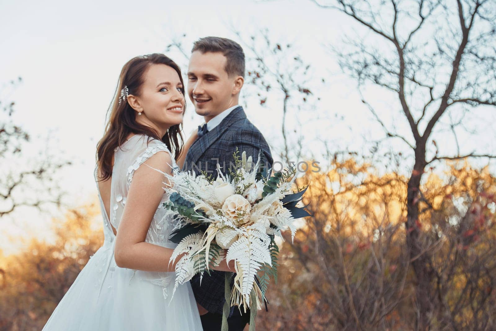 bride and groom holding beautiful bouquet in nature in autumn