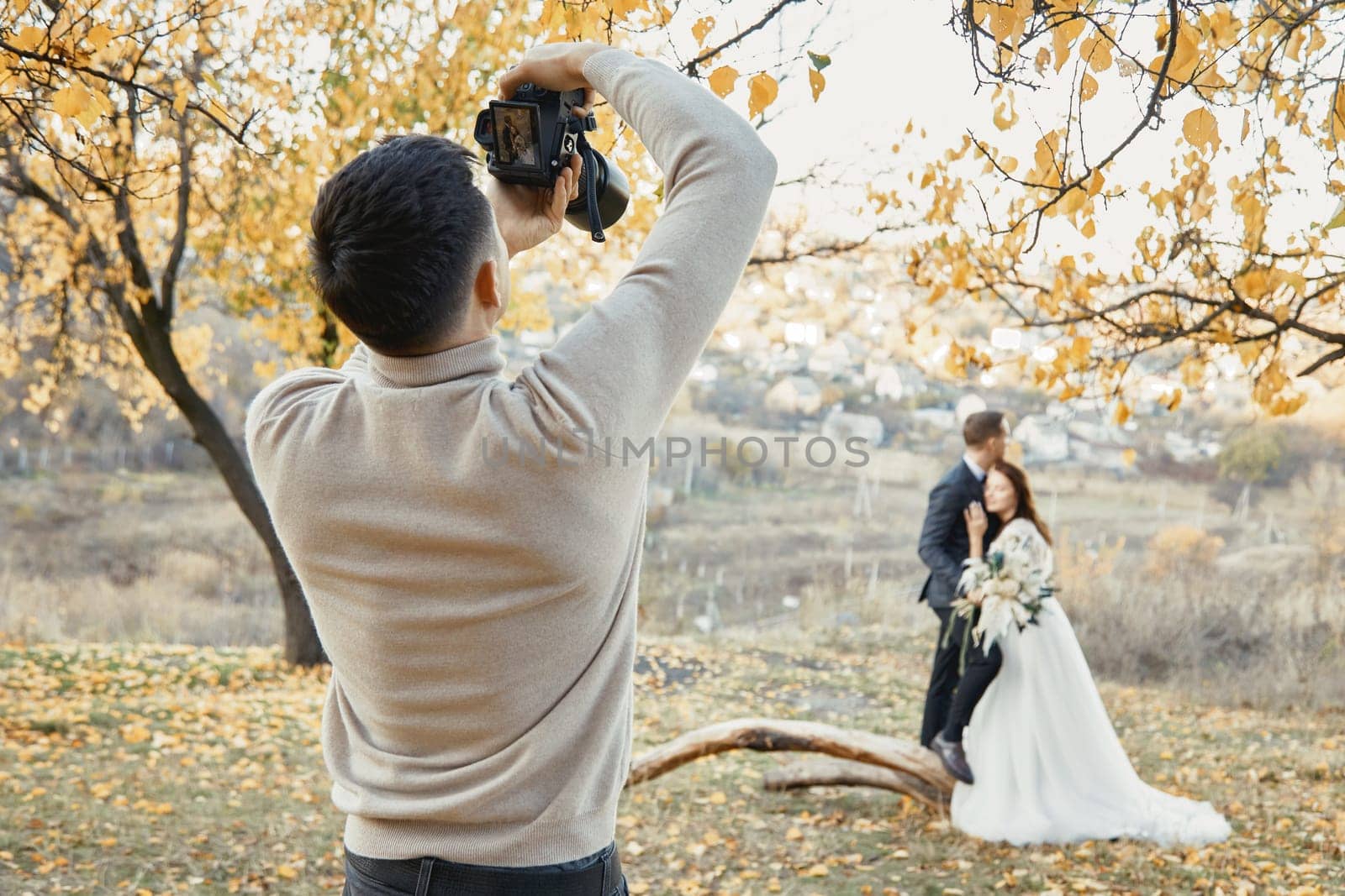 Professional wedding photographer in action. the bride and groom in nature in autumn