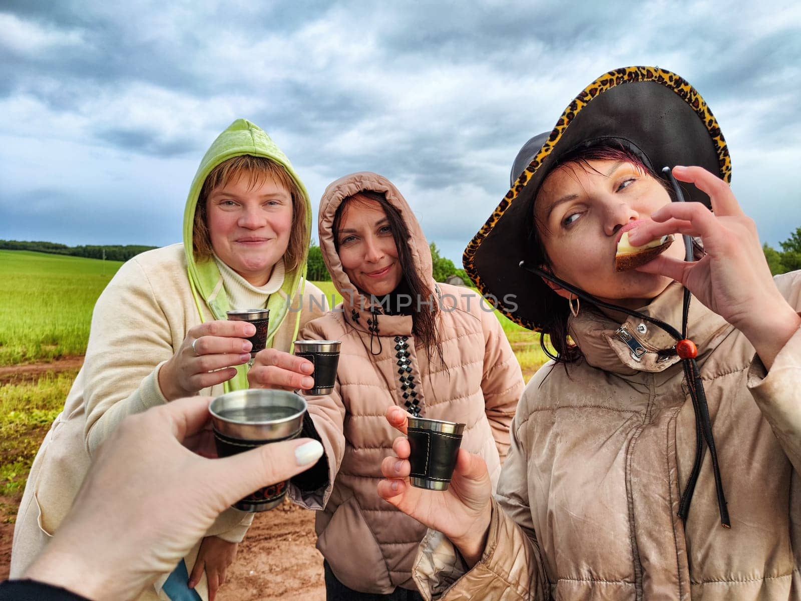 Middle-aged women or girls in the field in nature with glasses celebrating something on hike. Funny and happy Women in camping and travel by keleny