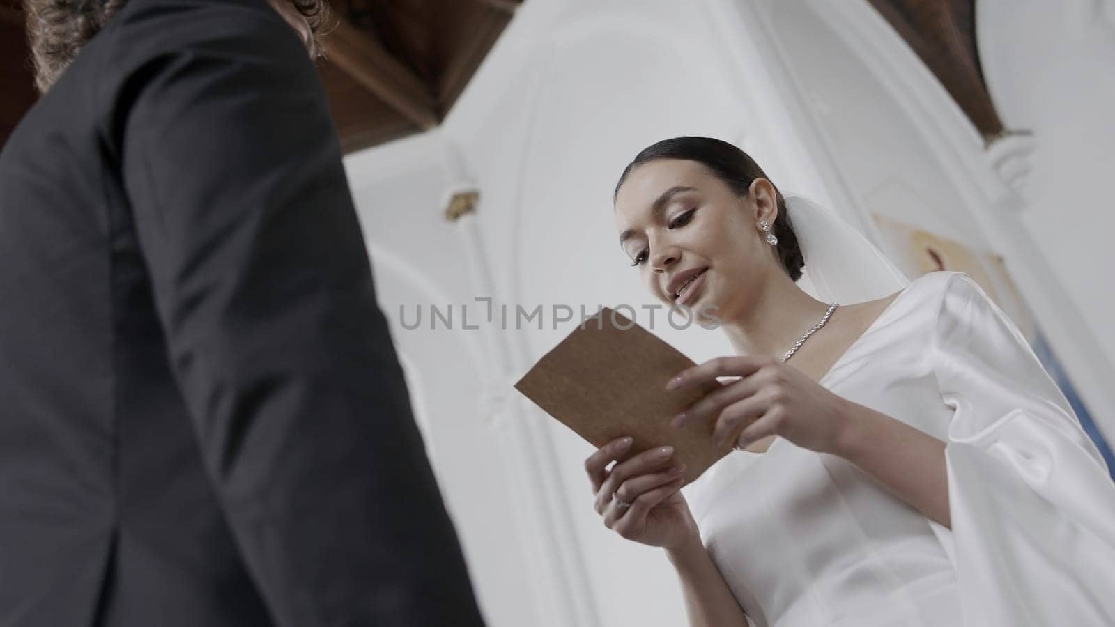 The wedding ceremony in the church. Action.Beautiful newlyweds with a bright spectacular bride in a white dress and a groom in a suit who take vows at their wedding. High quality 4k footage