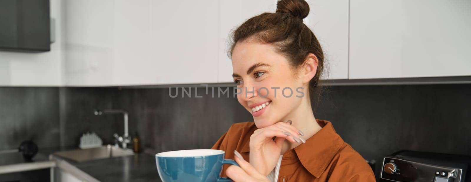 Beautiful young woman with big cup of coffee, smiling and looking happy.