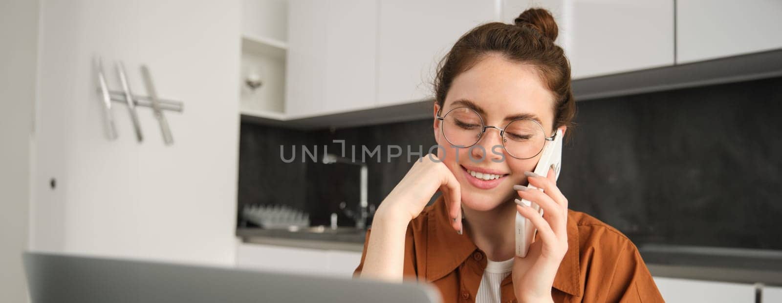 Portrait of young woman at home, doing online shopping. Businesswoman has own start-up making a phone call, has conversation with client, saleswoman trading online, using laptop by Benzoix