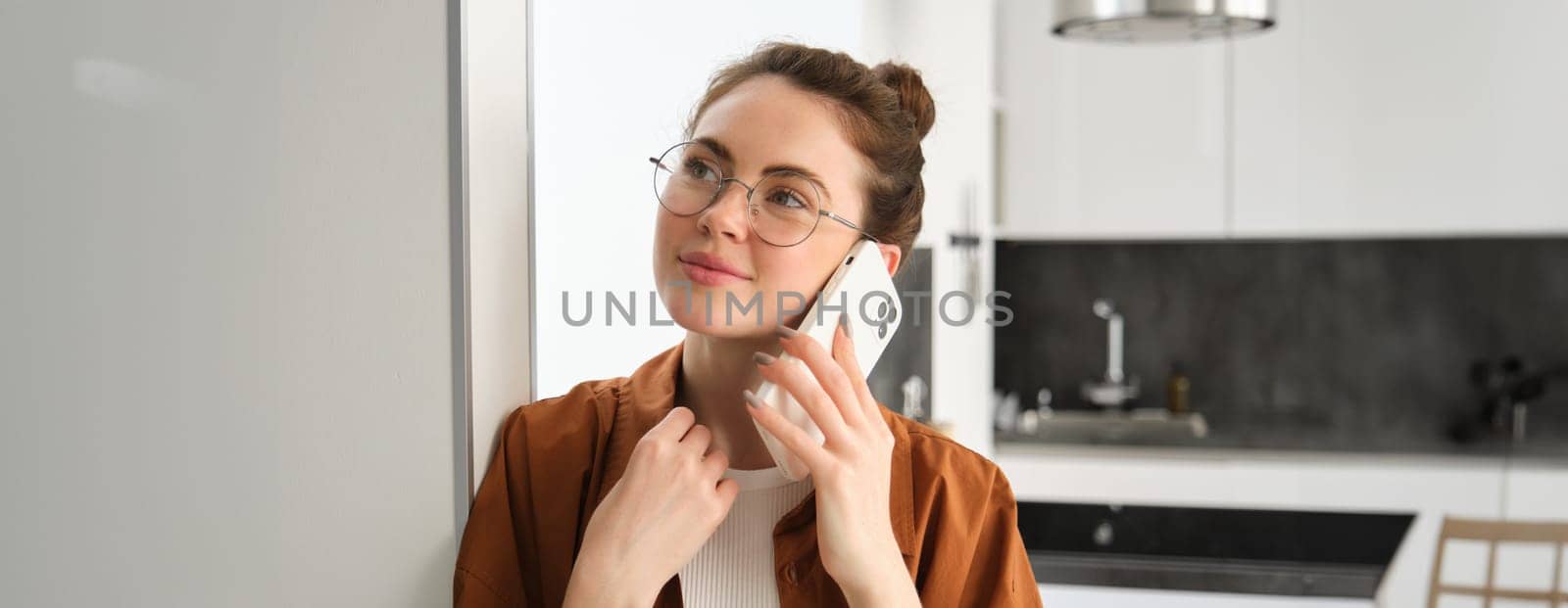 Portrait of happy woman at home, answers phone call, talking on mobile, holding smartphone and smiling.