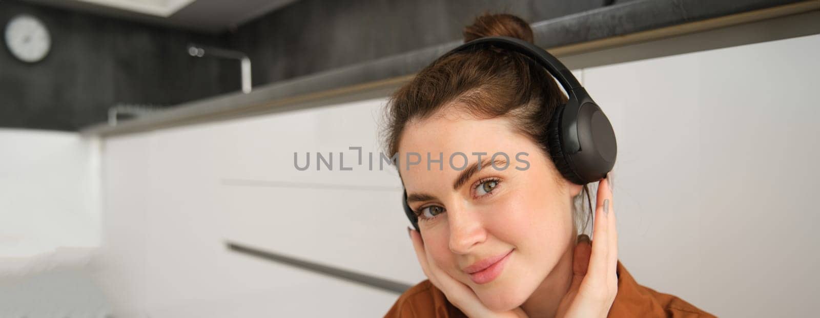 Cute smiling girl in wireless headphones, listens to music in earphones.