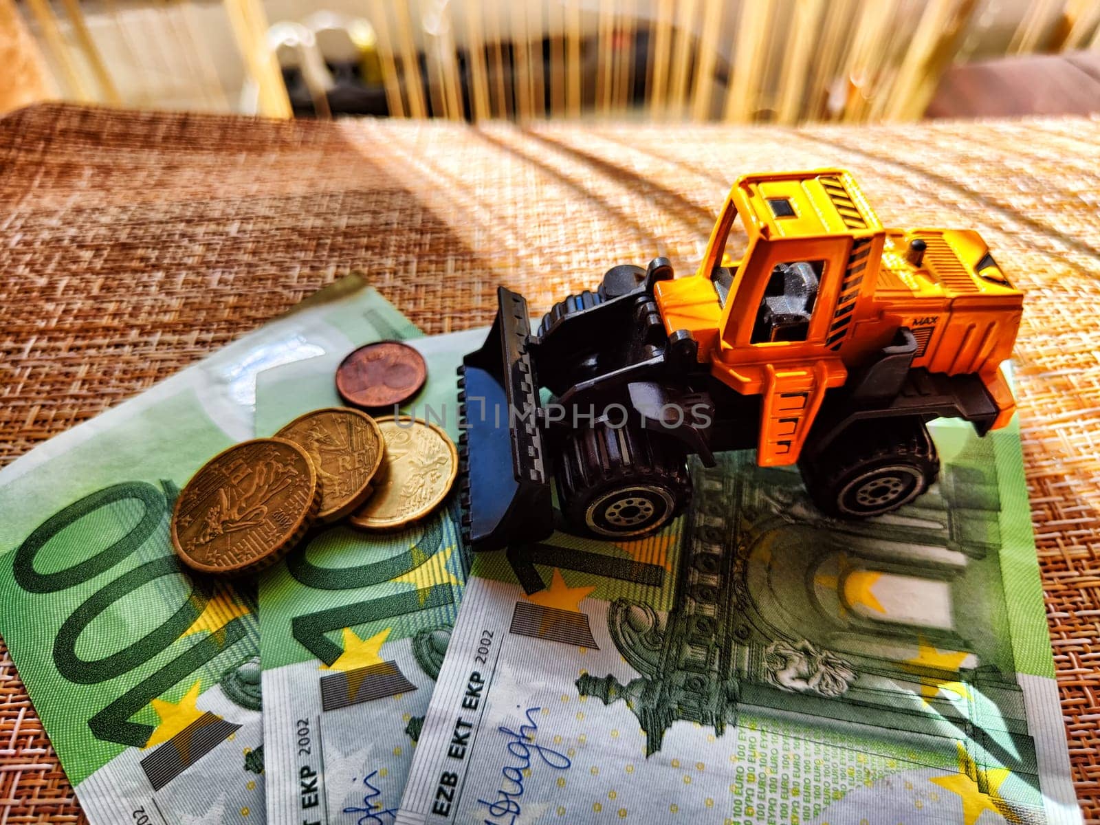 A small toy tractor or excavator on bundle of money. The concept of the high cost of technology. The possibility of earning money with construction machinery