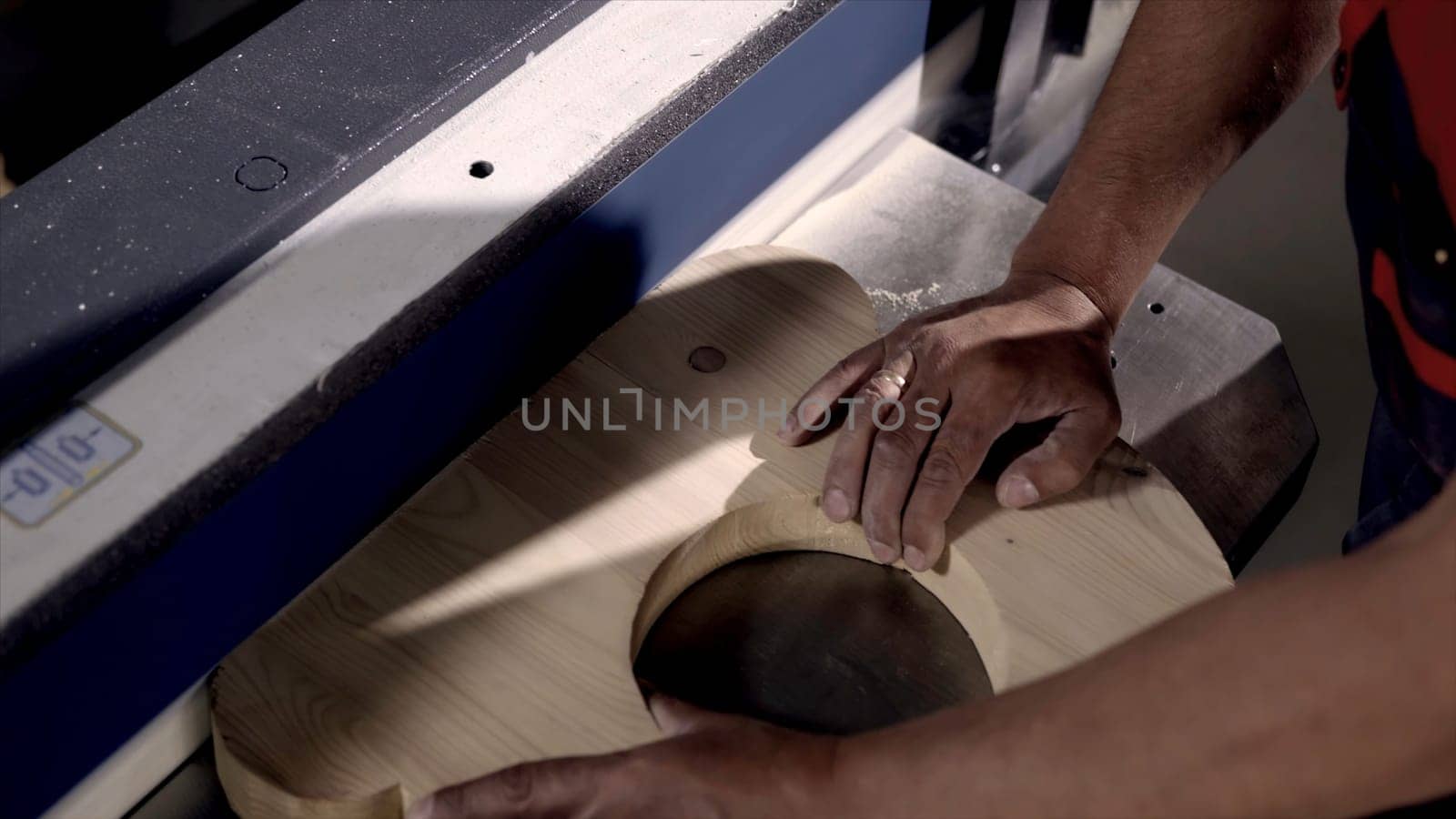 Close-up of man grinds wood products on industrial machine. Action. Carpenter polishes wooden product for tape manufacturing machine.