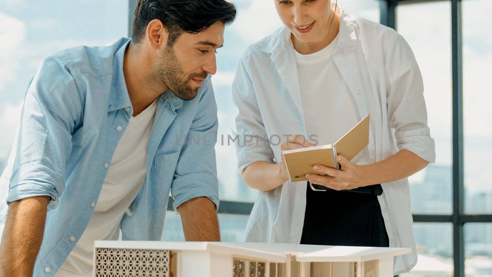 Skilled architect engineer team discussion about house model construction. Smart interior designer sharing, talking about building design while beautiful coworker taking a note. Design. Tracery