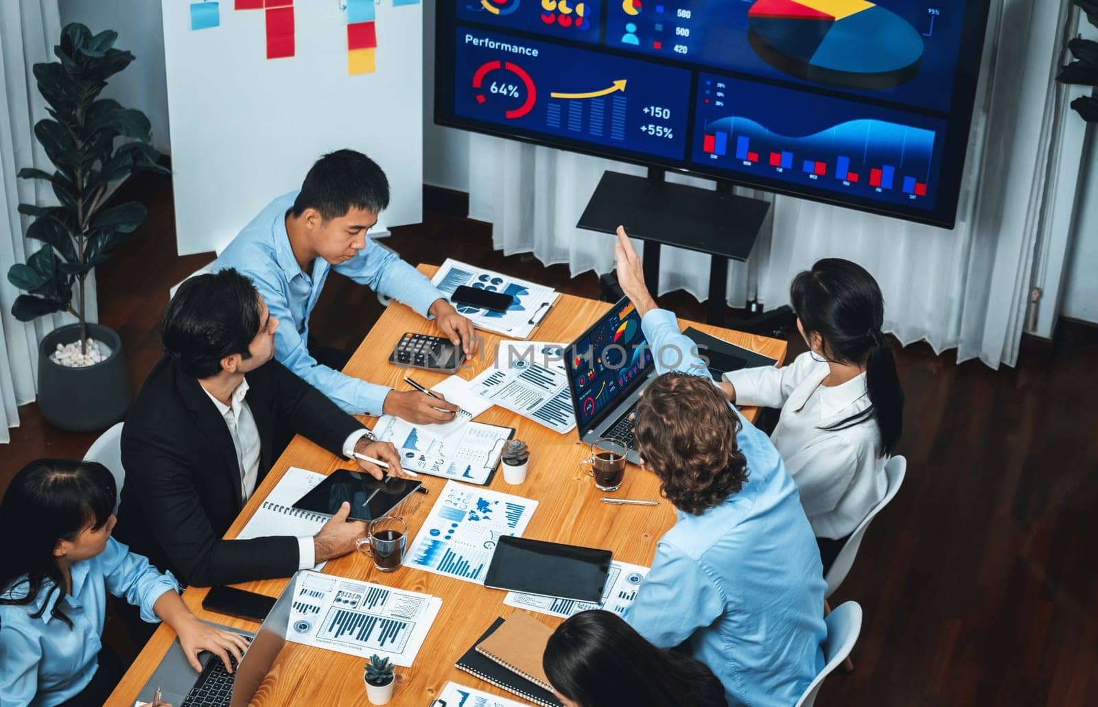 Wide top view of diverse group of business analyst team analyzing financial data report paper on meeting table. Chart and graph dashboard by business intelligence analysis. Meticulous