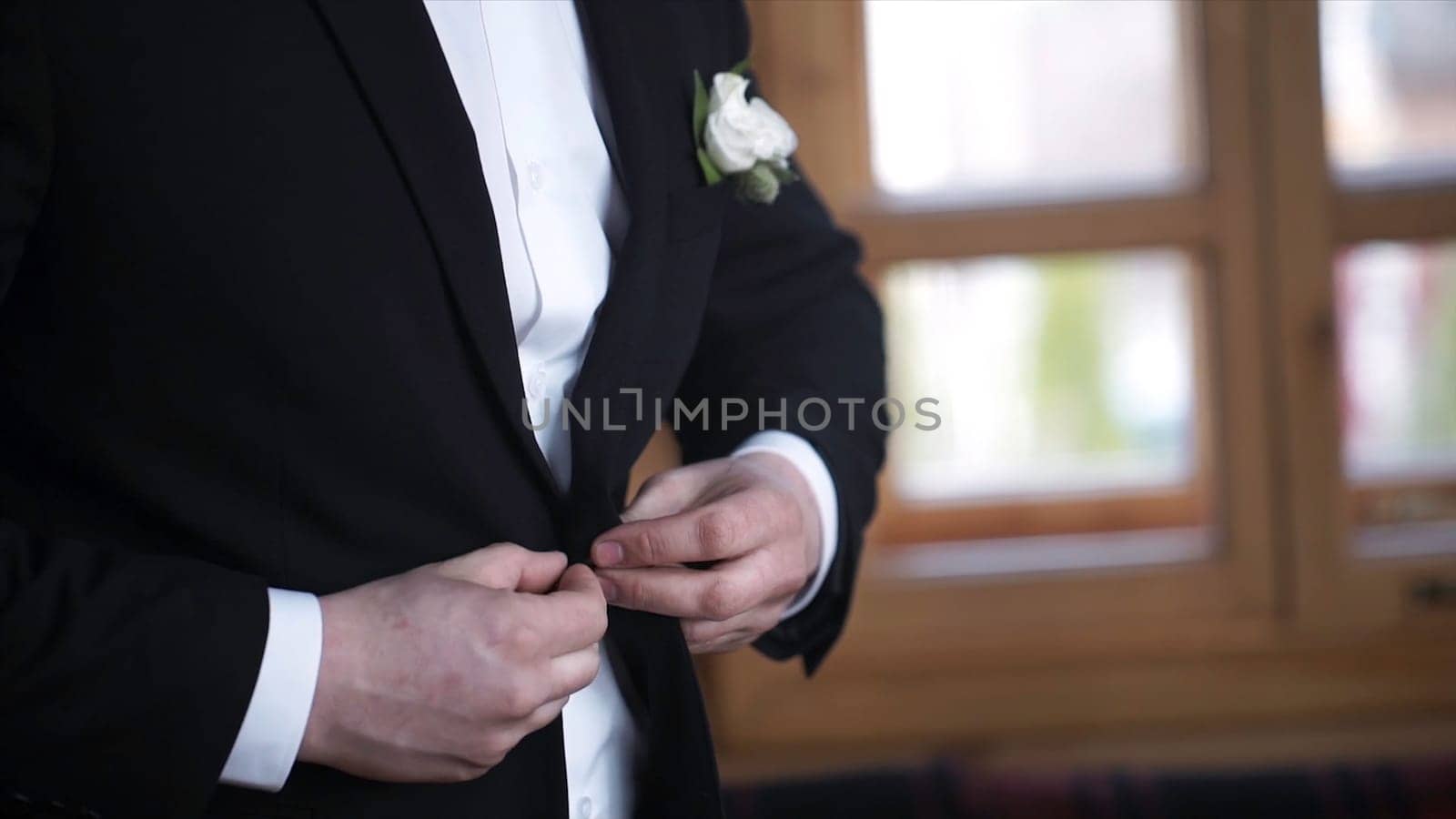 Man buttoning on a black jacket. Wedding details - elegant groom dressed wedding tuxedo costume is waiting for the bride. businessman buttoning jacket, getting dressed. Groom buttons jacket HD