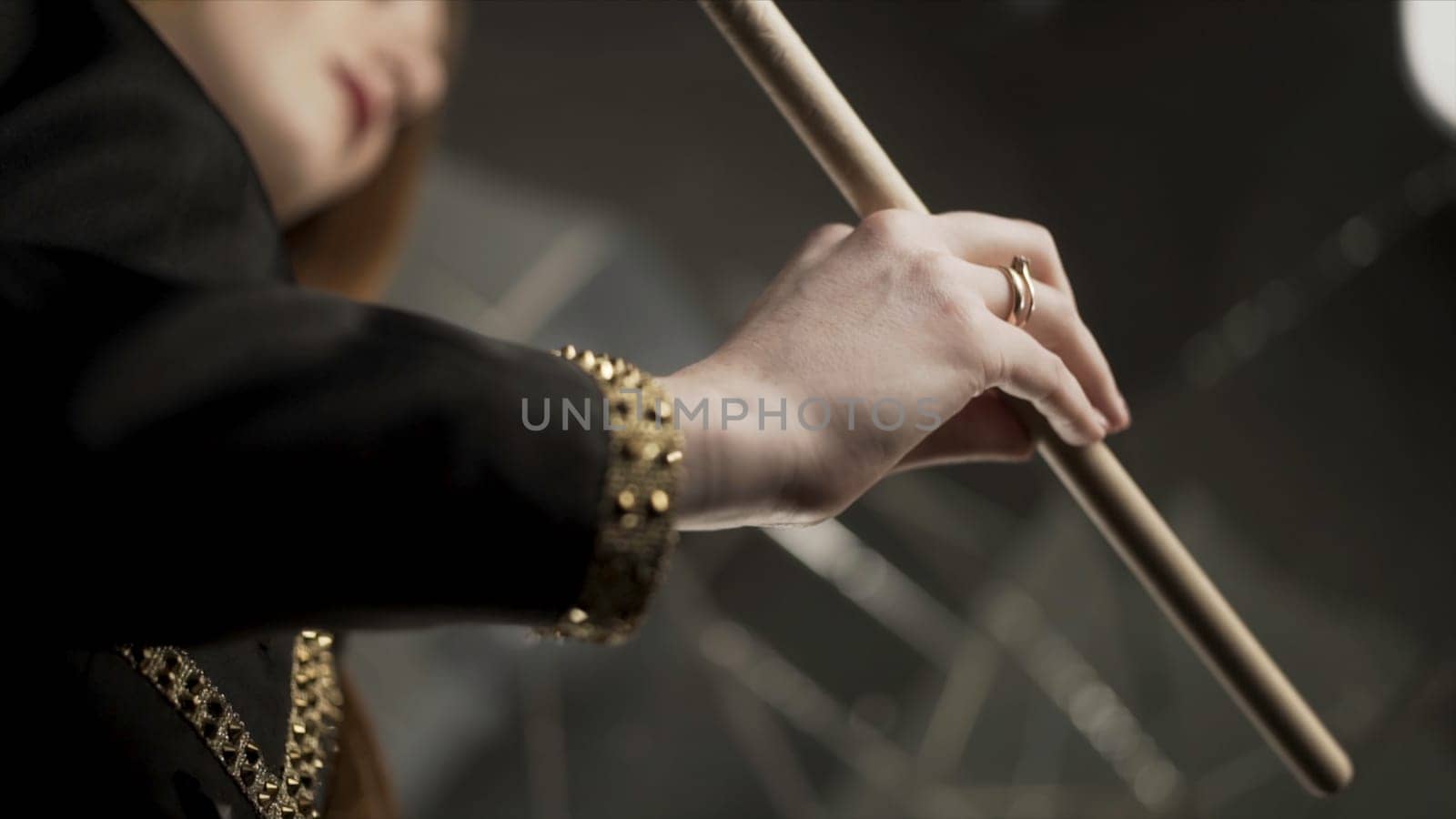 Young attractive woman hand holding drumstick and rotating it during musical rehearsal. Close up for woman hand with manicure and gold rings holding and spinning a drumstick.