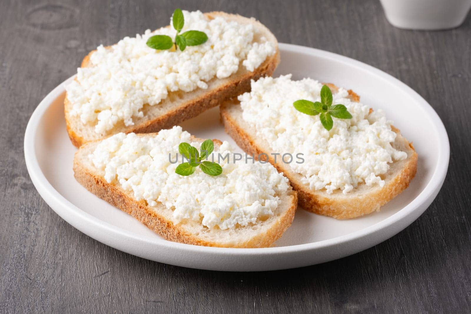 Sandwiches with cottage cheese in a plate on a wooden table.