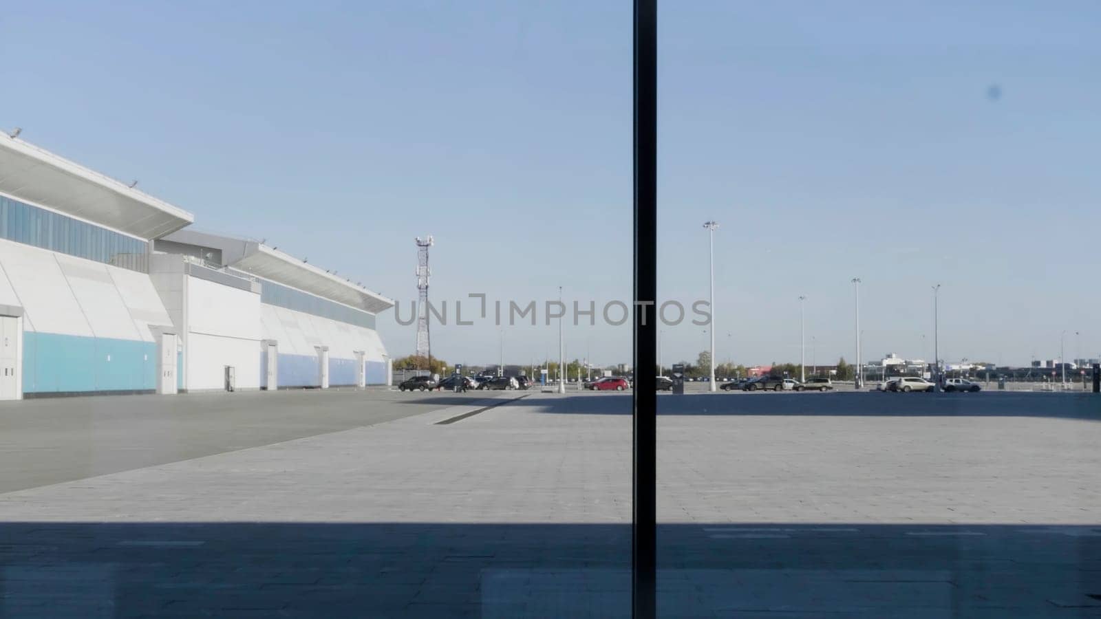 A silhouette of a businessman using smartphone, having phone call and walking in front of panoramic windows. HDR. Serious man with a smartphone indoors by the window on blue sky background