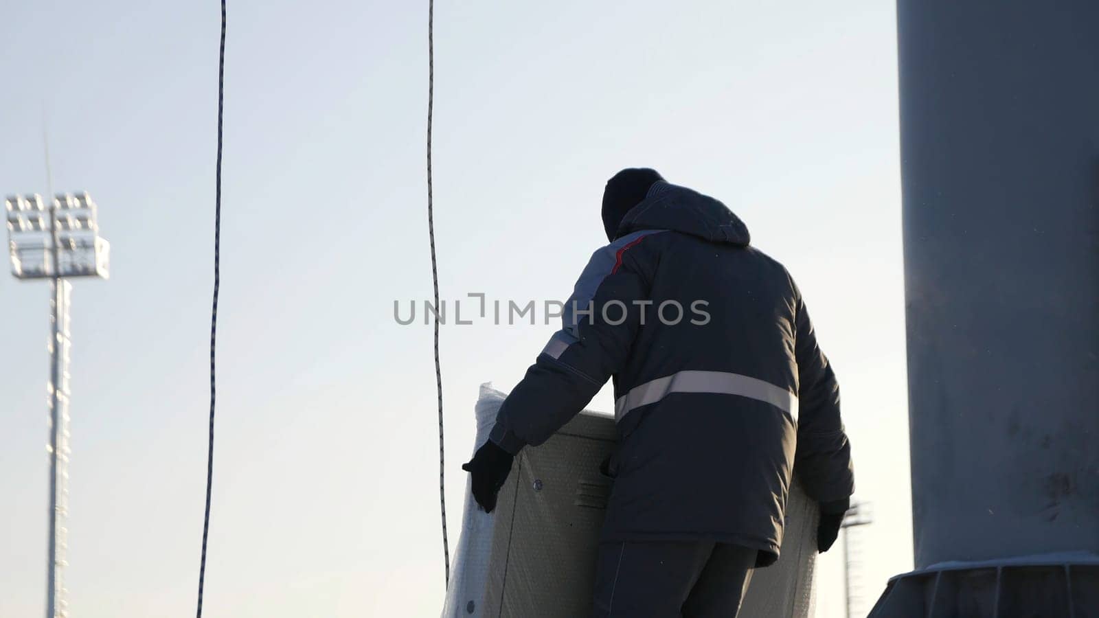 Man assemble Billboard. A man collects parts of the Billboard for advertising in the winter time.