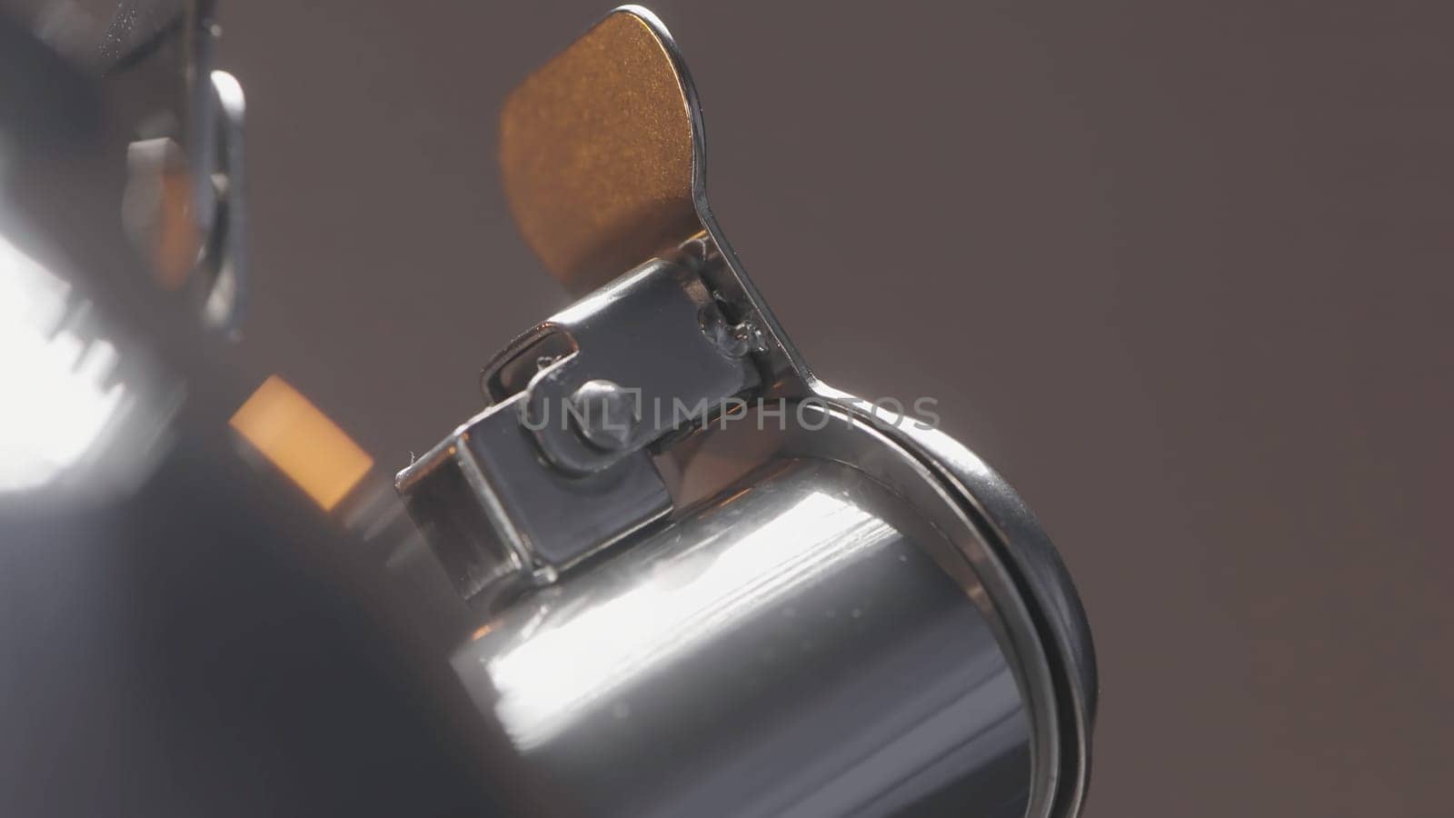 Close up of spinning closed short spout of a metal silver kettle on blurred grey wall background. Action. Spinning new teapot