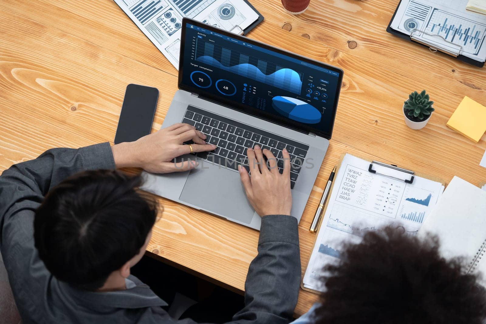 Multiracial analyst team use BI Fintech software to analyze financial data on meeting table. Financial dashboard data display on laptop screen with analyzed chart for marketing indication. Concord