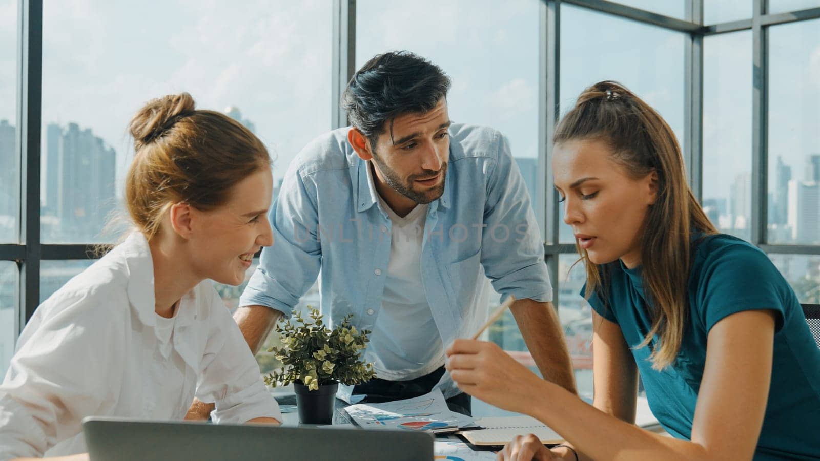 Group of skilled businesspeople sharing idea about marketing plan. Professional business team working together, discussing, talking at meeting table with laptop, document with cityscape. Tracery